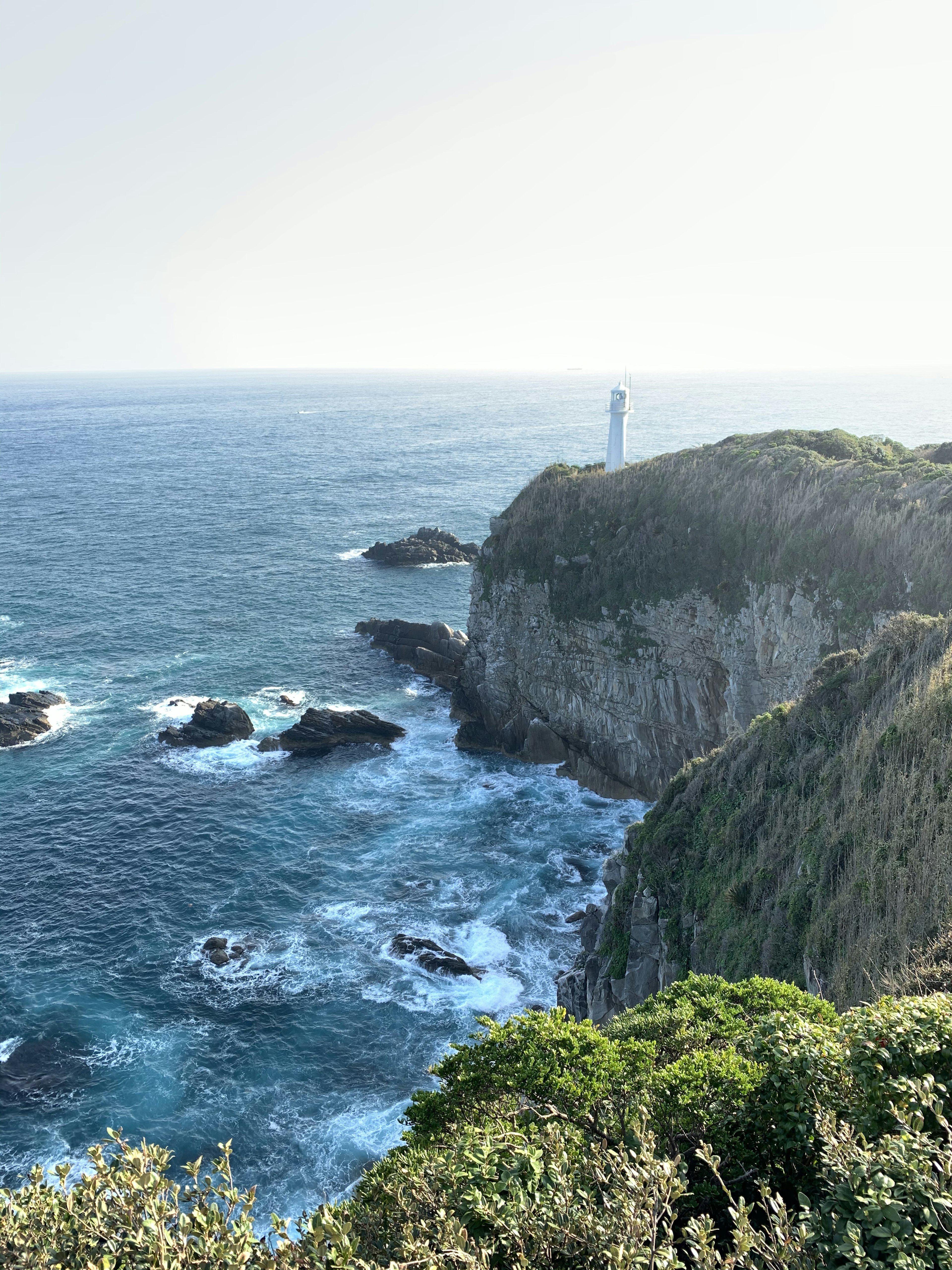 Scogliera costiera con un faro che sovrasta il mare blu e le onde bianche