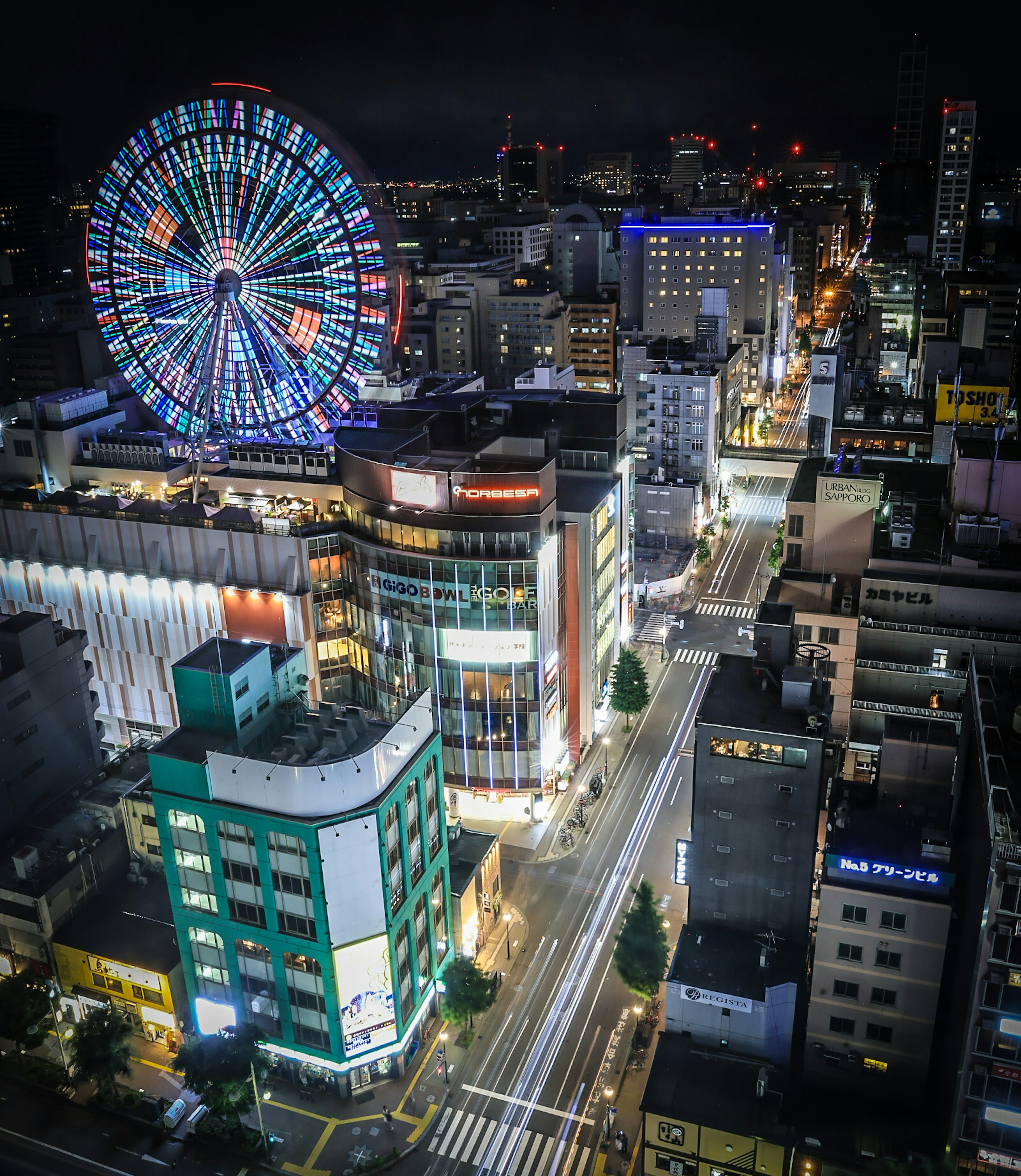 Paesaggio urbano notturno con ruota panoramica colorata e edifici illuminati