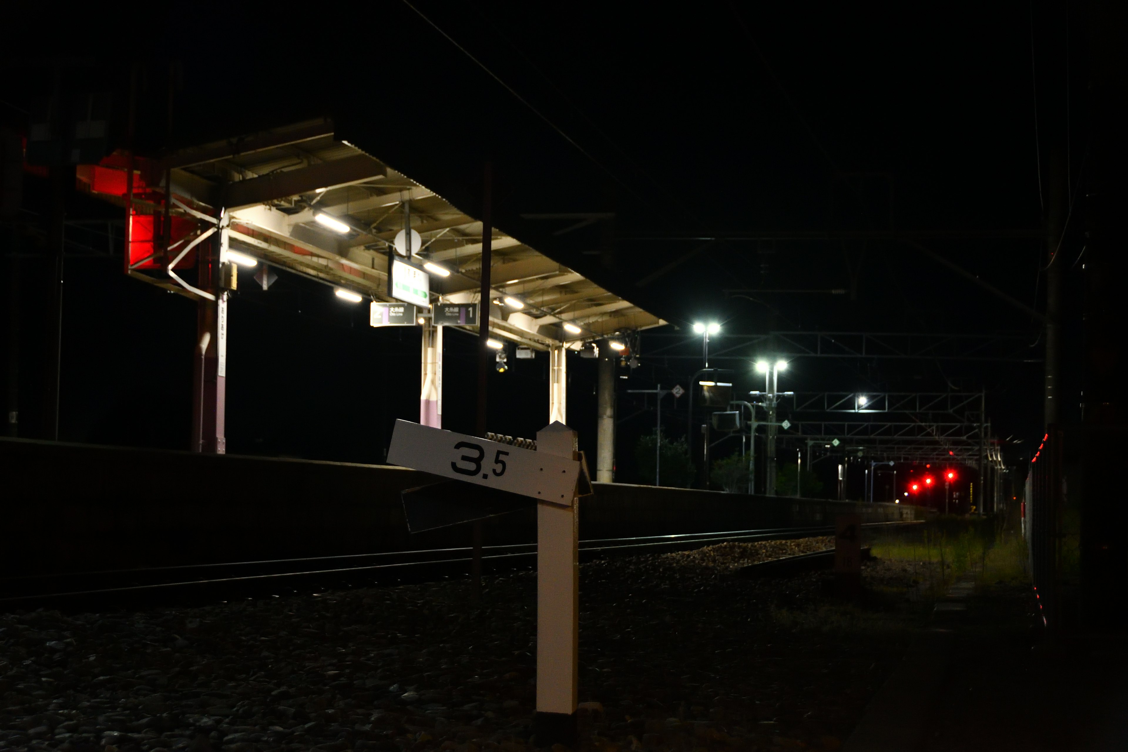 Platform stasiun kereta malam dengan sinyal yang menyala