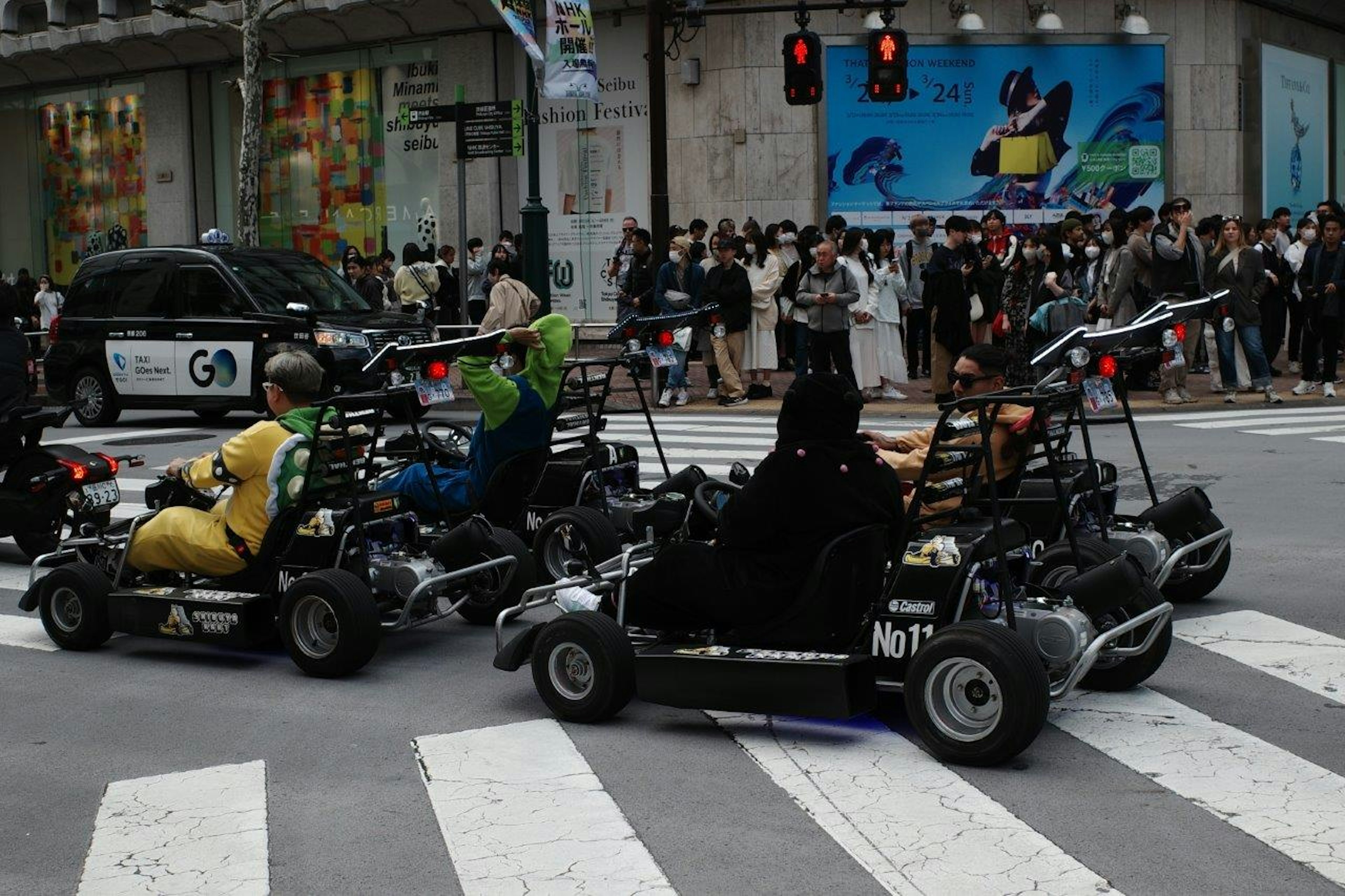 Người dân lái go-kart tại vạch qua đường với nền thành phố và đèn giao thông