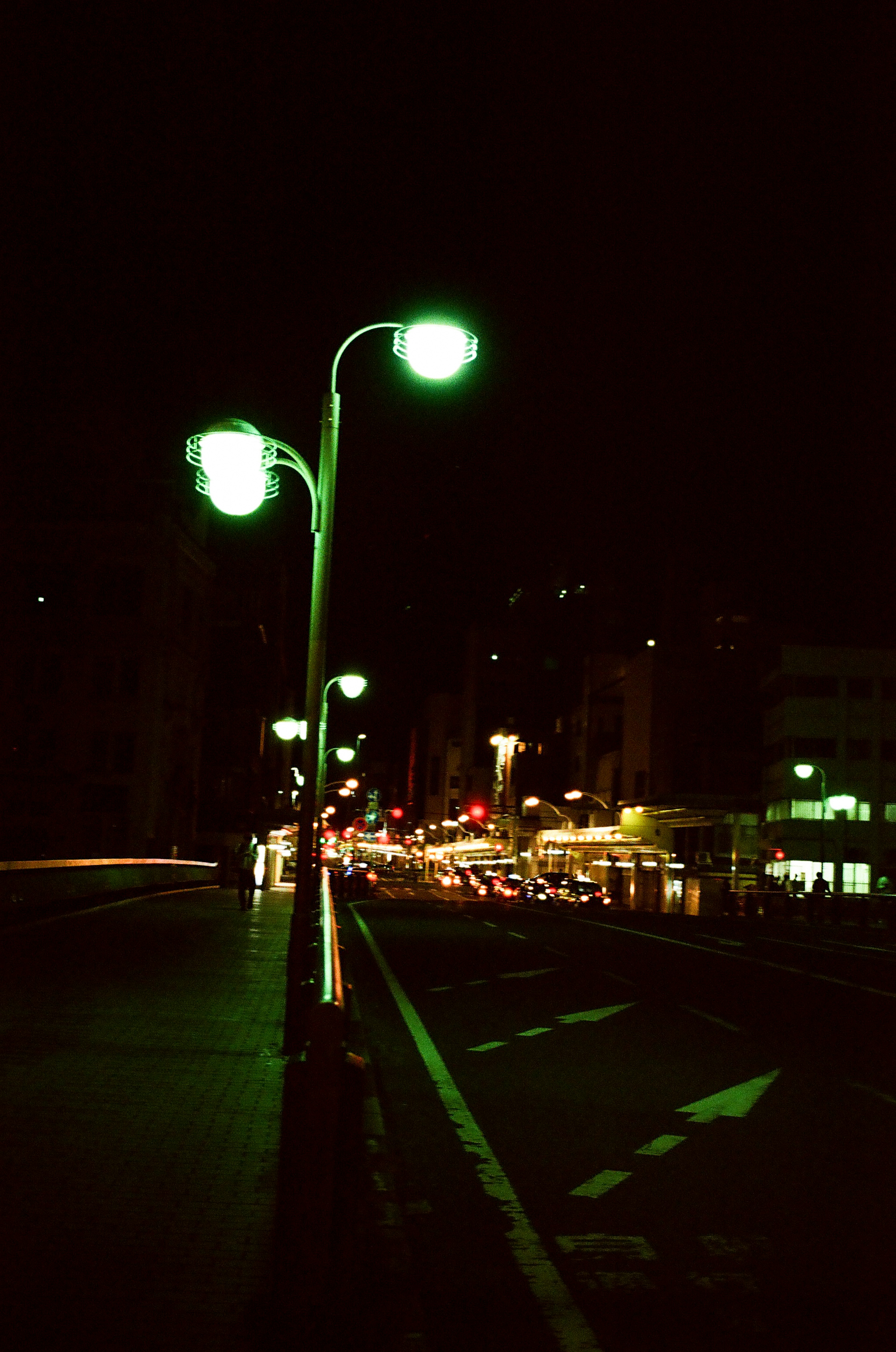 Urban street scene at night with glowing green streetlights