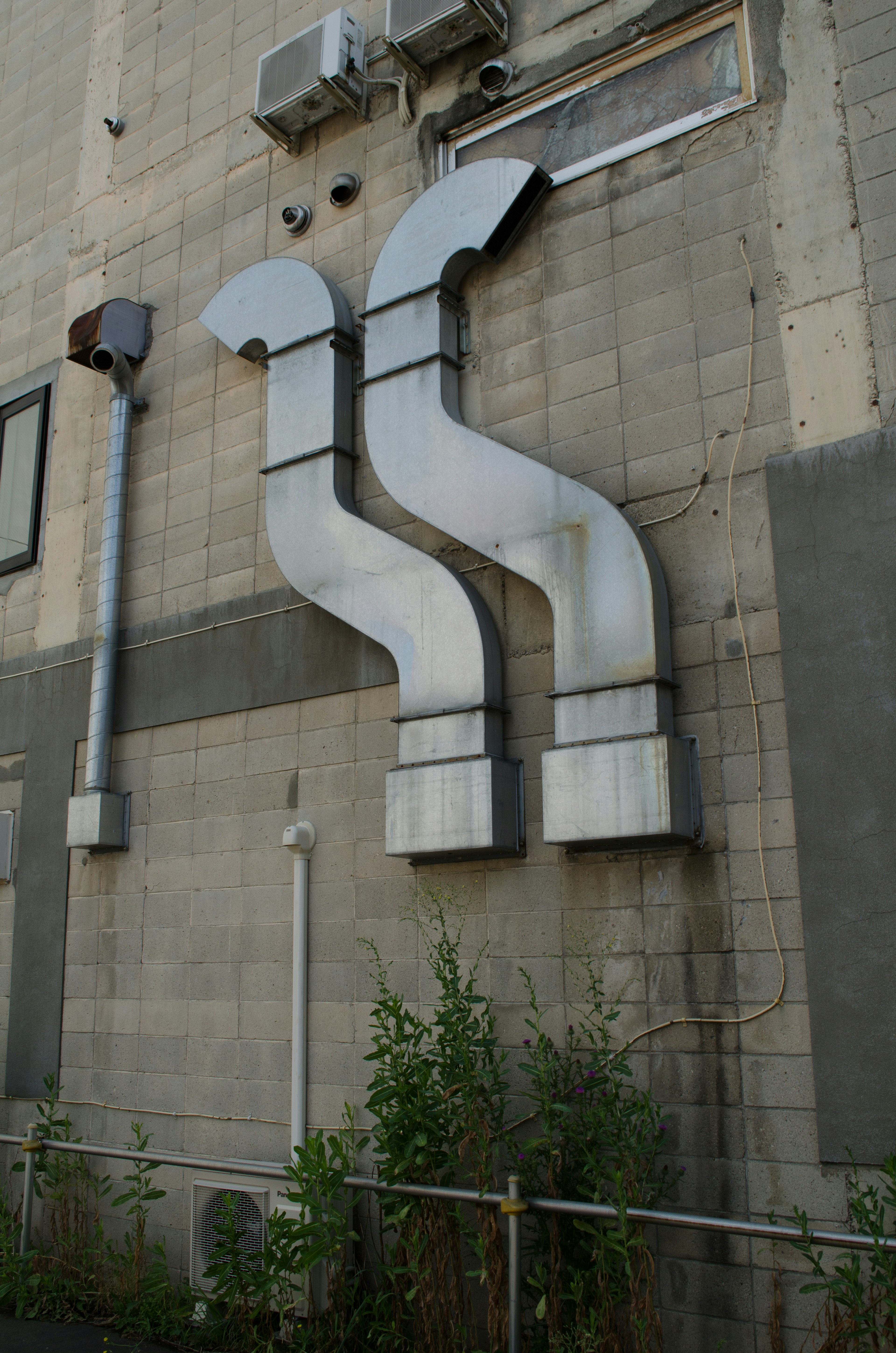 Design unico di condotti di ventilazione in metallo attaccati a un muro di cemento