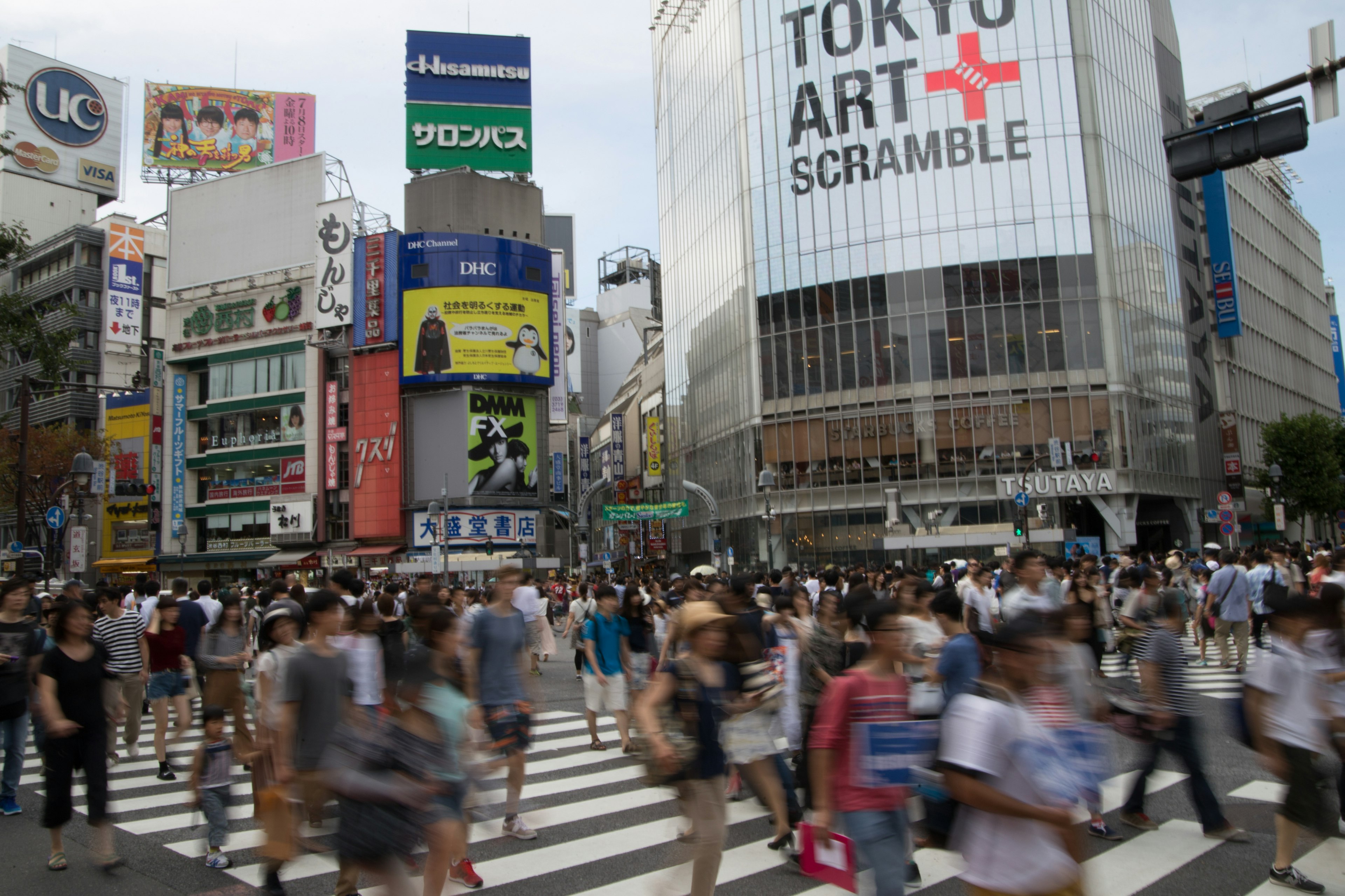 渋谷のスクランブル交差点で人々が行き交う様子とアートイベントの看板