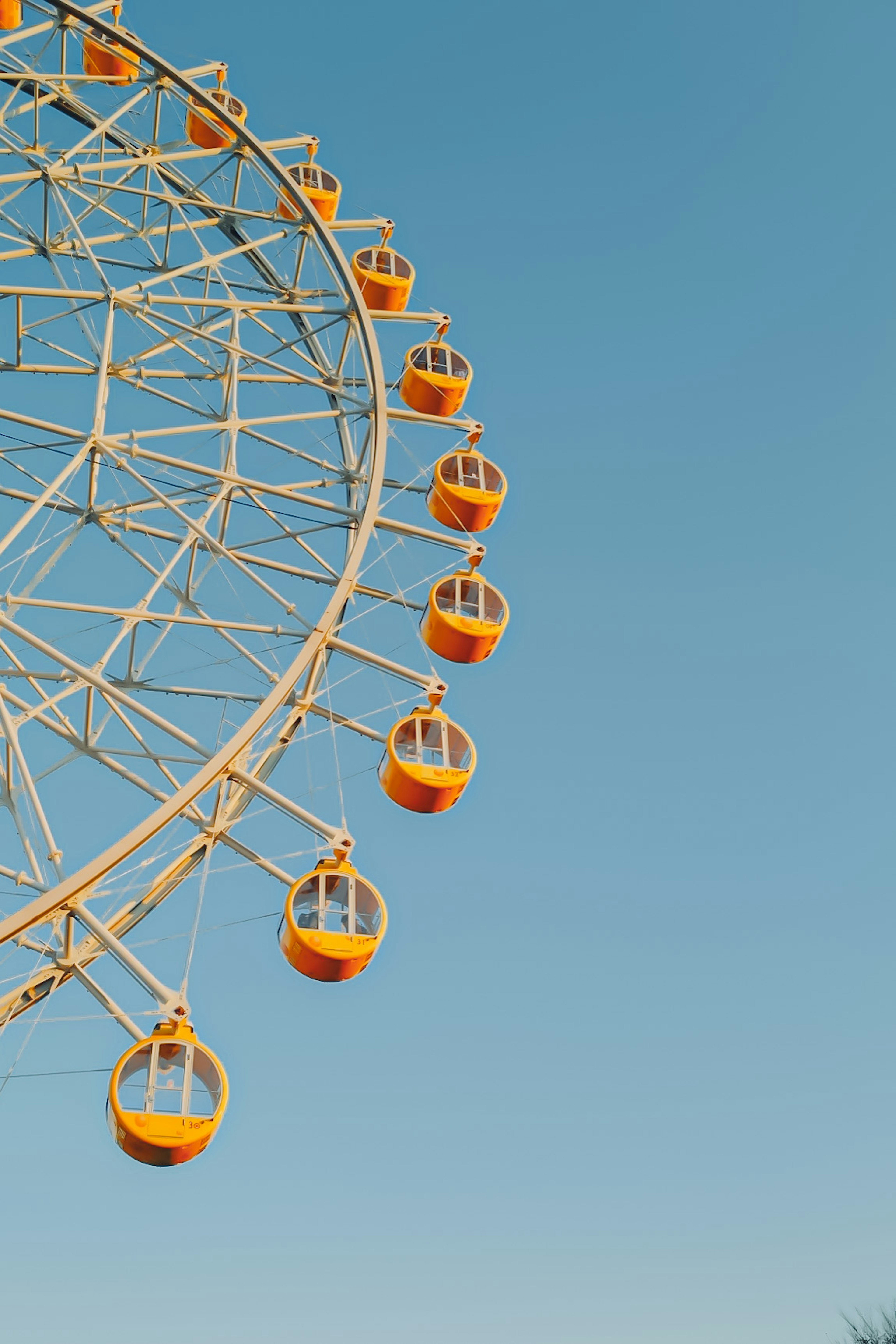 Parte di una ruota panoramica sotto un cielo blu con cabine gialle