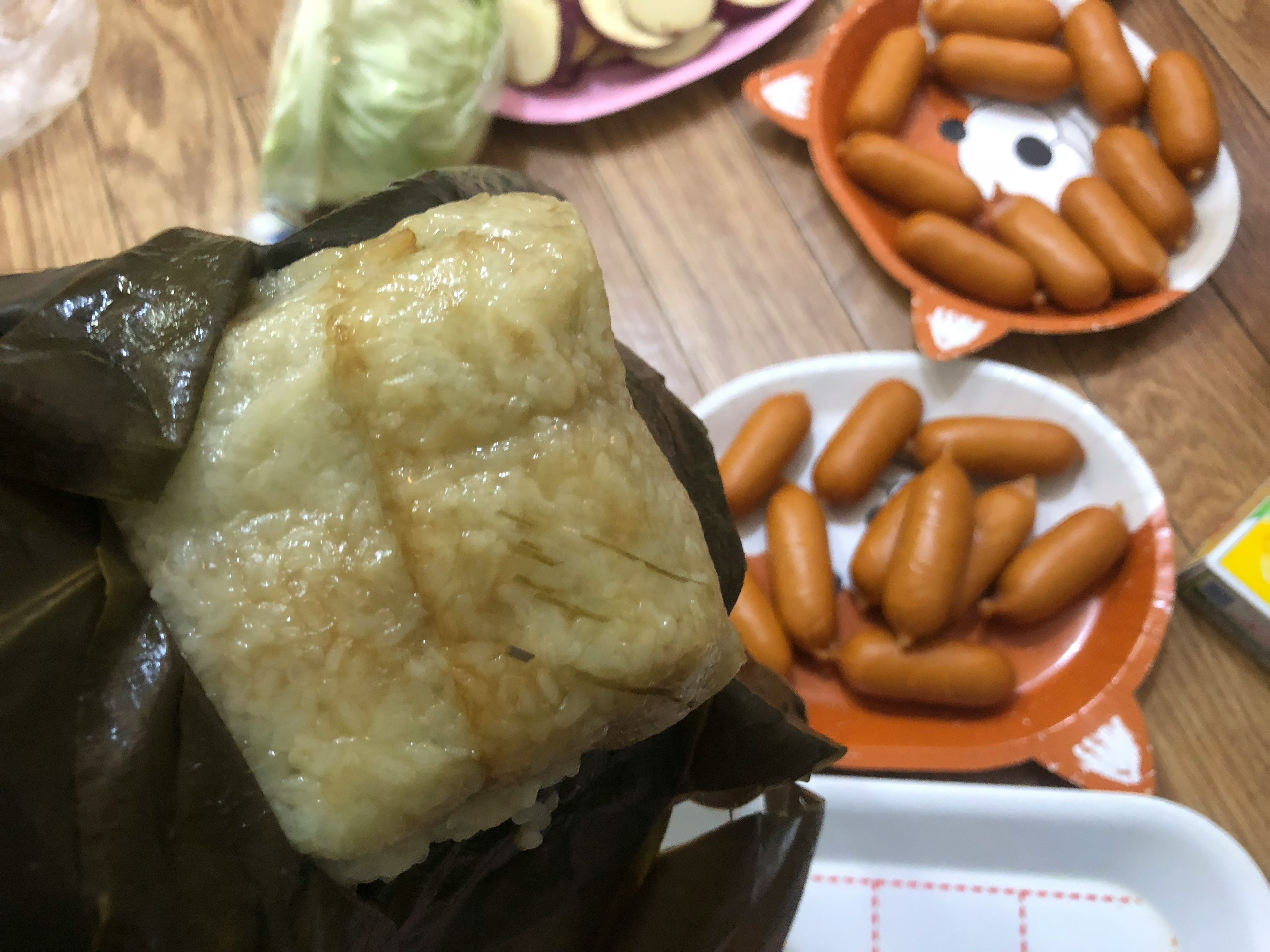 葉に包まれたおにぎりと周囲の食べ物