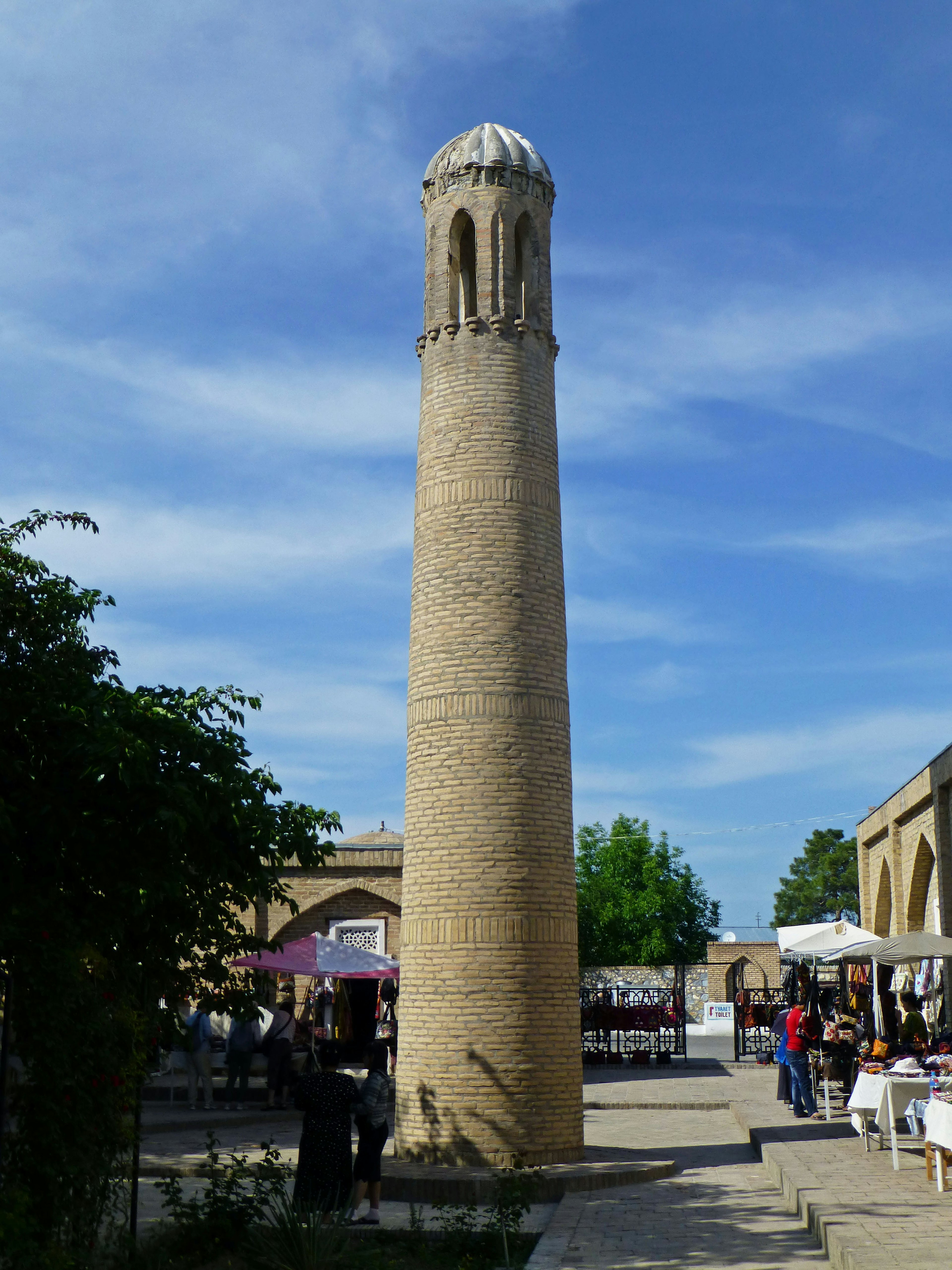 Hoher Ziegelturm unter blauem Himmel mit umliegendem Markt