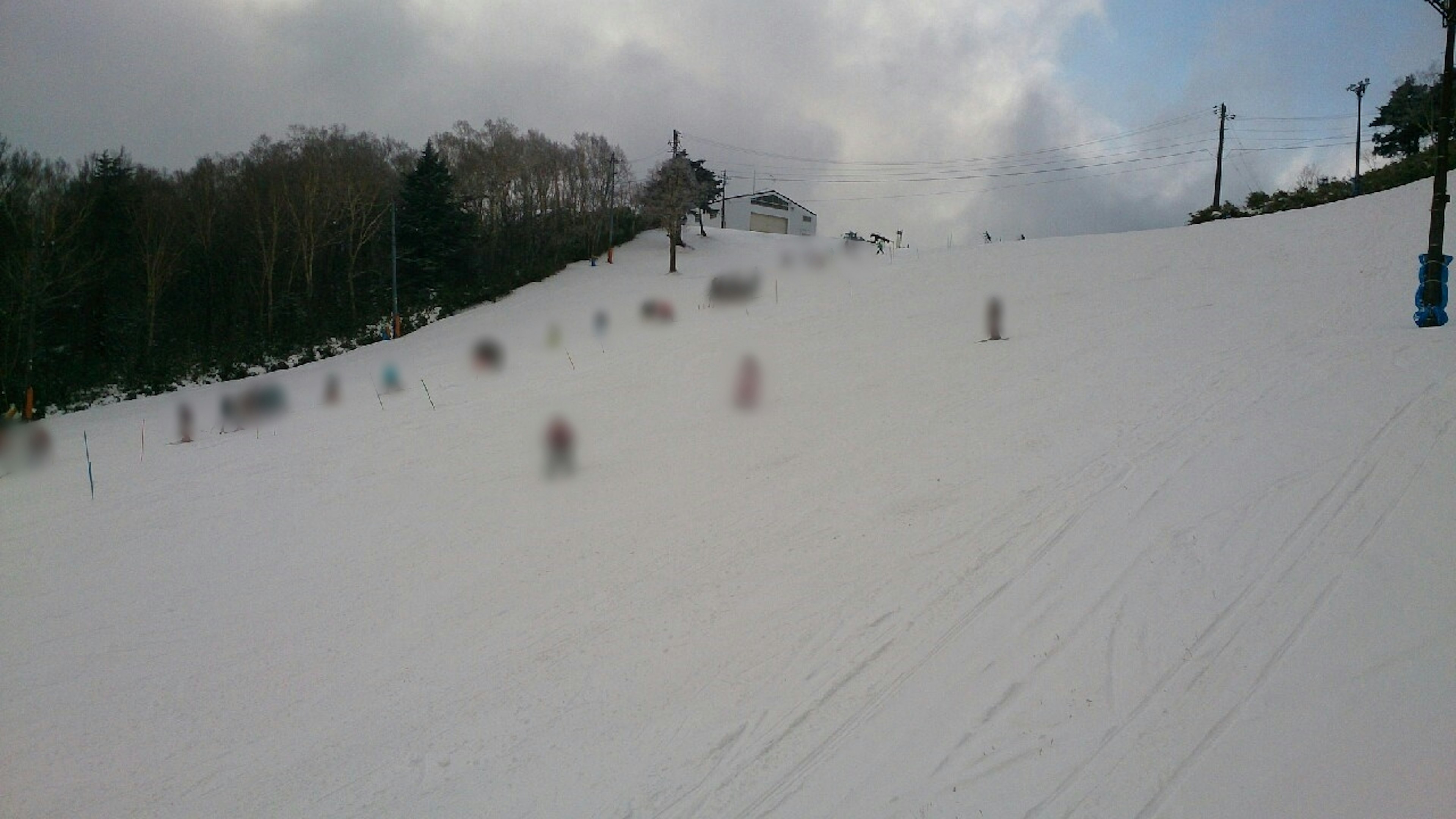 Lintasan ski yang tertutup salju dengan pemain ski dan langit mendung