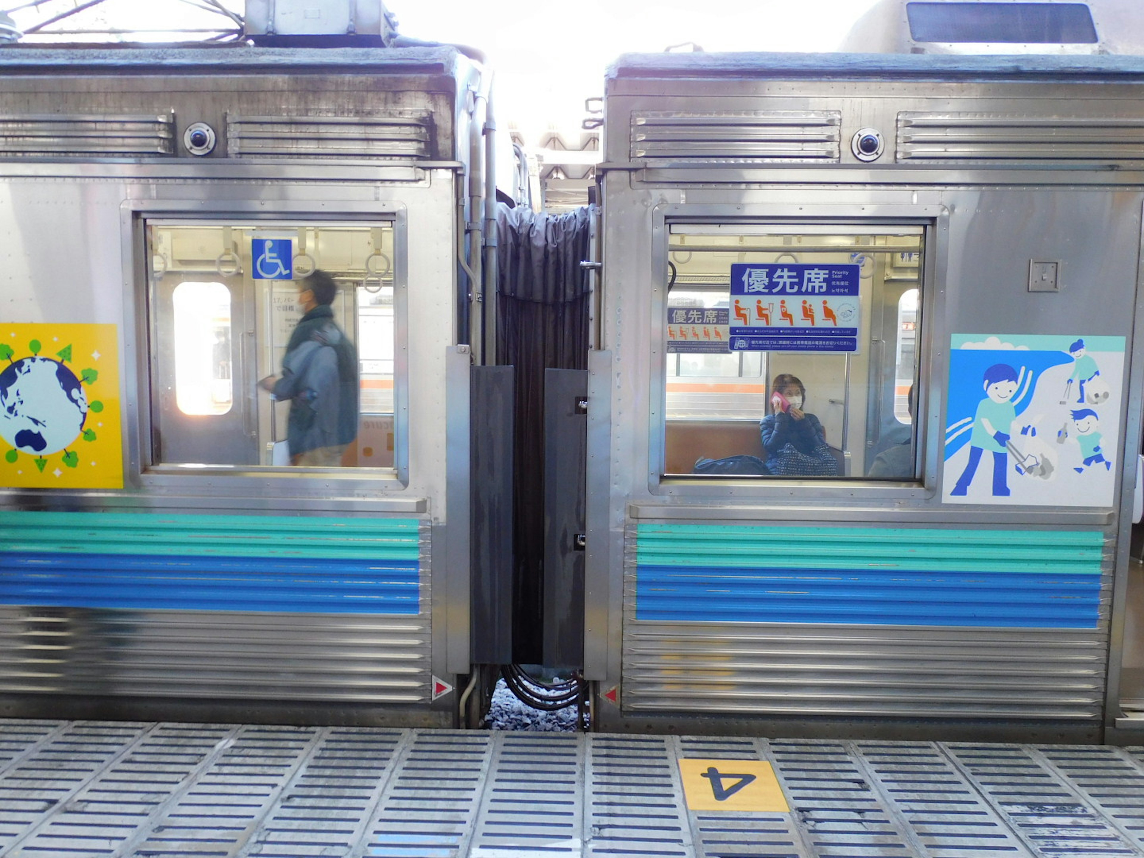 2つの電車のドアの間に立つ乗客とカラフルなアートワーク