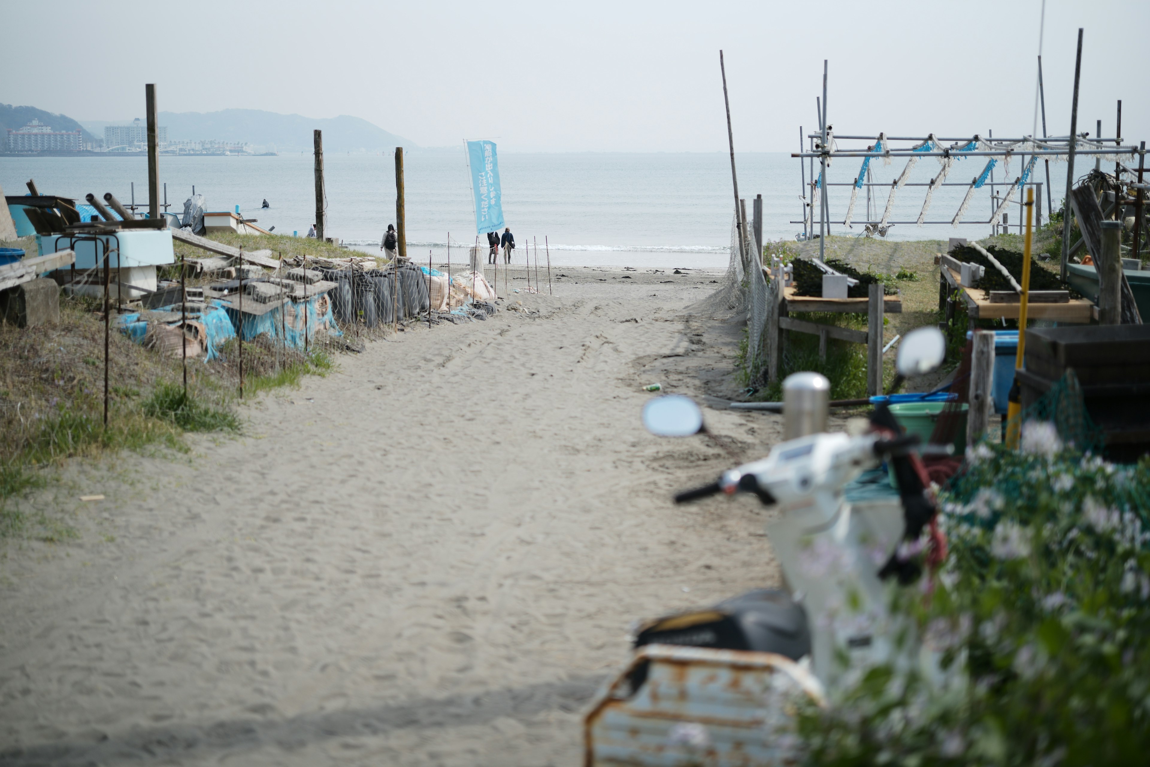 Sentier menant à la plage avec des silhouettes au loin et l'océan