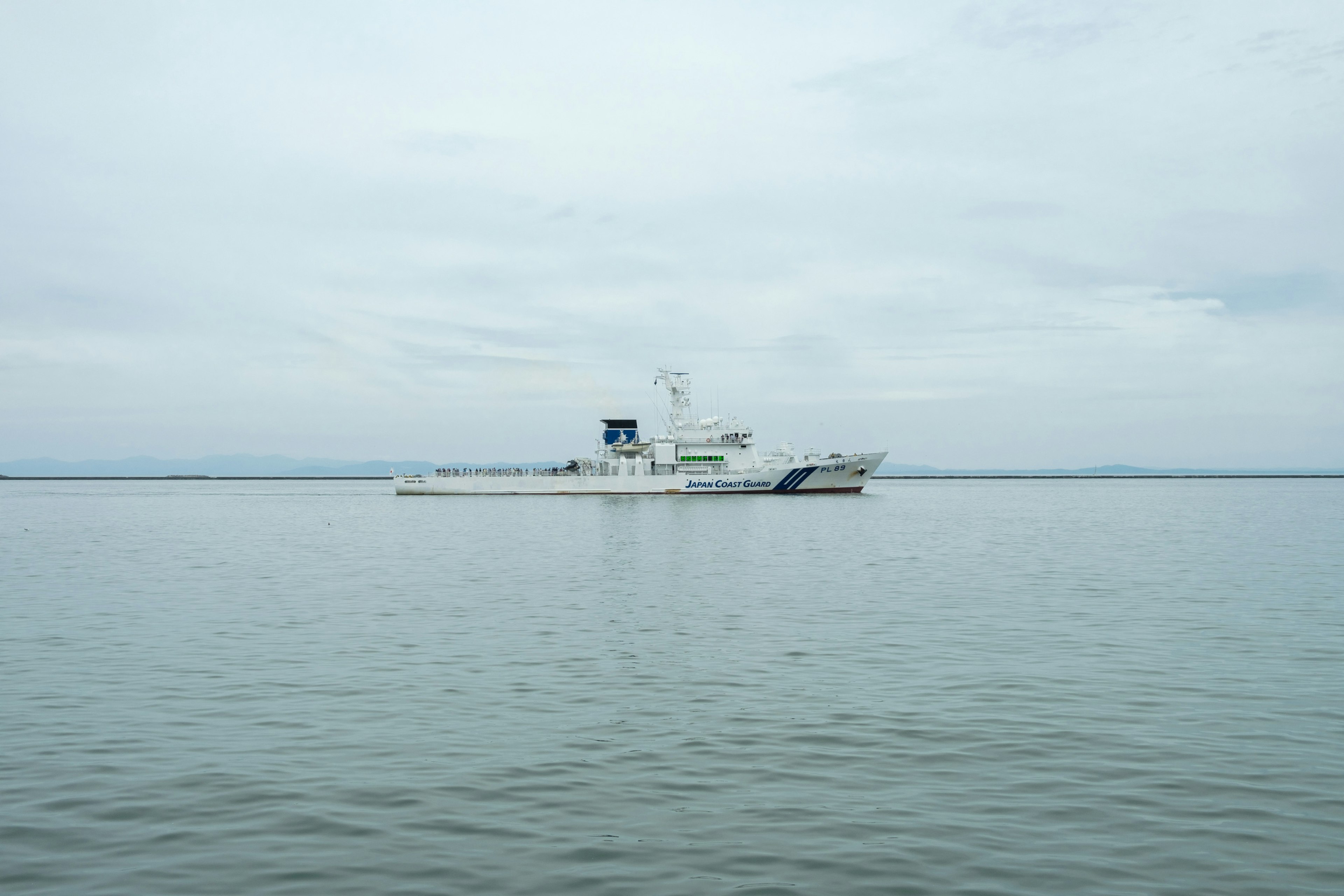 Ein weißes Schiff, das auf ruhigem Wasser unter einem grauen Himmel schwimmt