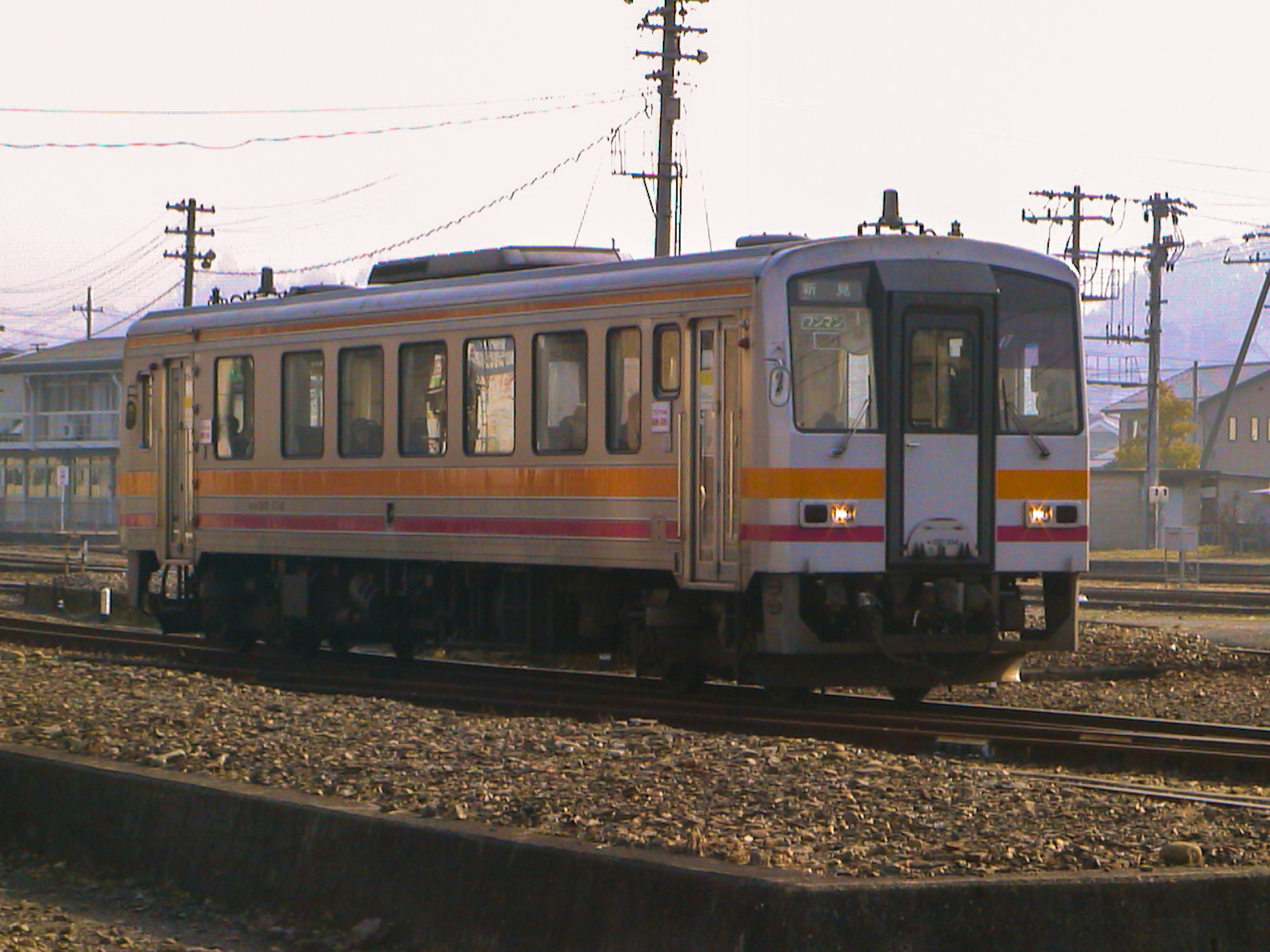 一列帶有橙色條紋的日本火車在軌道上行駛