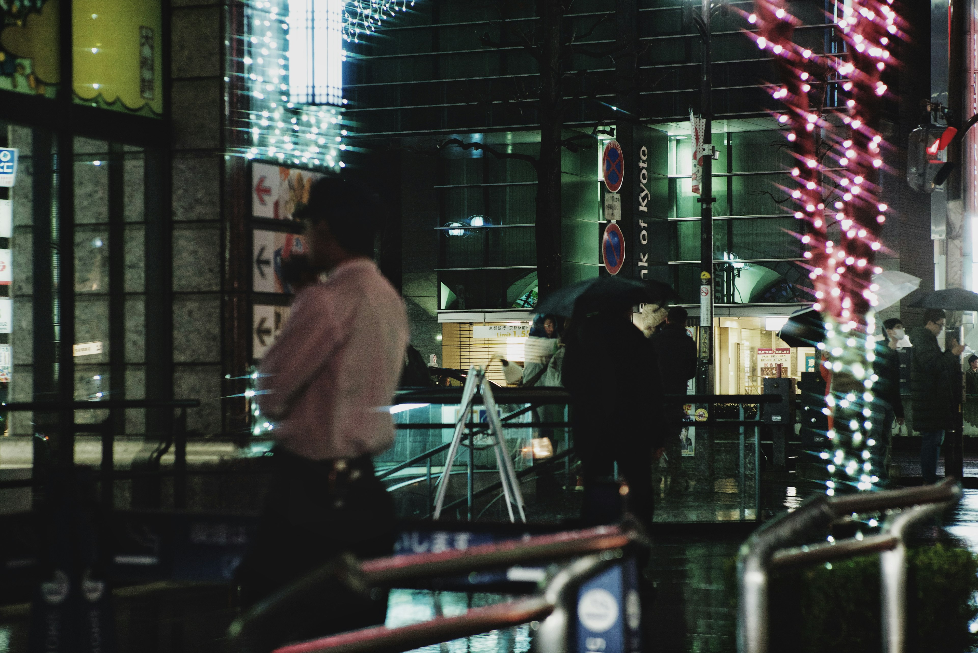 Paisaje urbano nocturno con personas caminando y luces coloridas