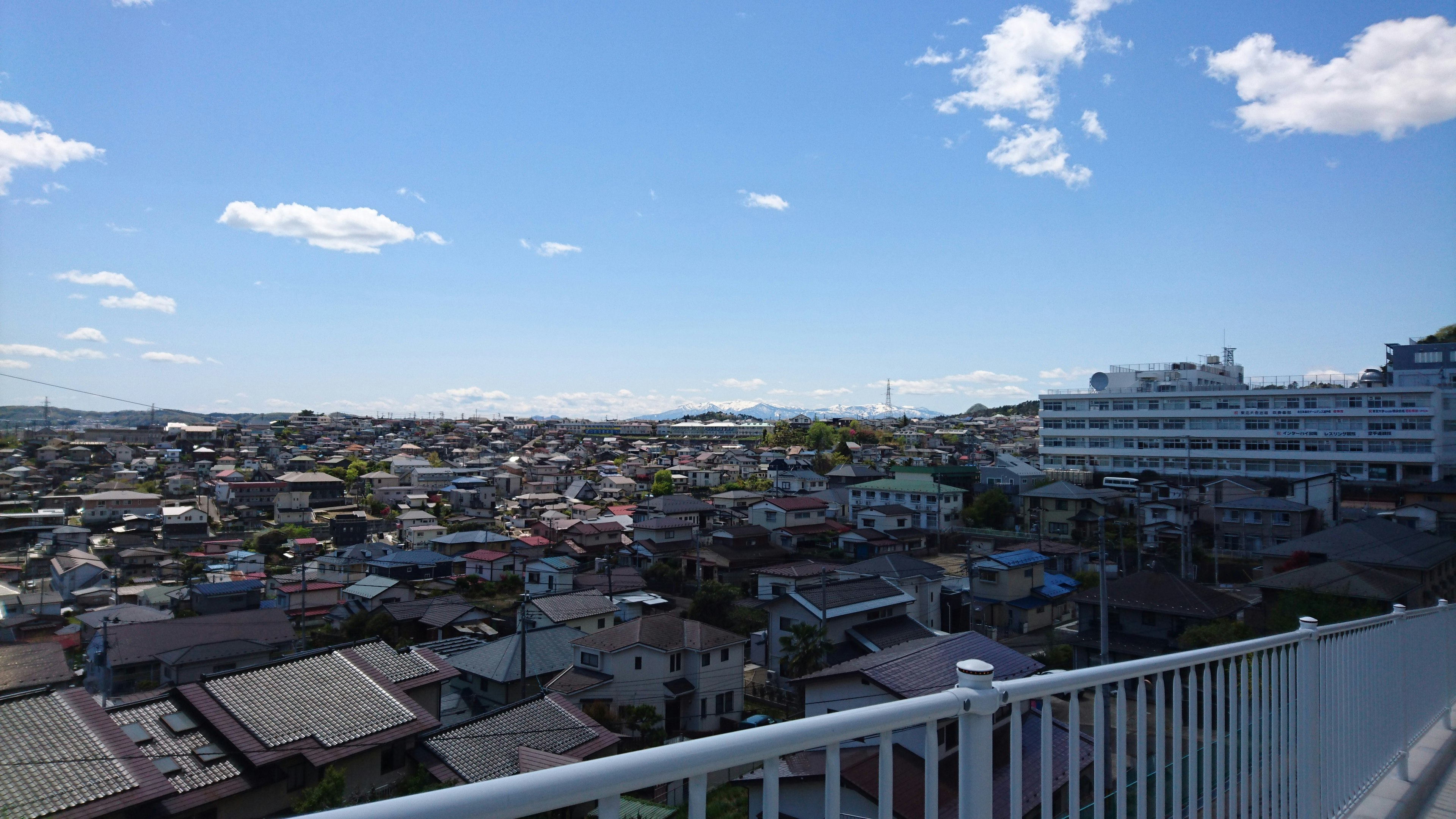 A view of a residential area under a blue sky with nearby buildings and distant mountains