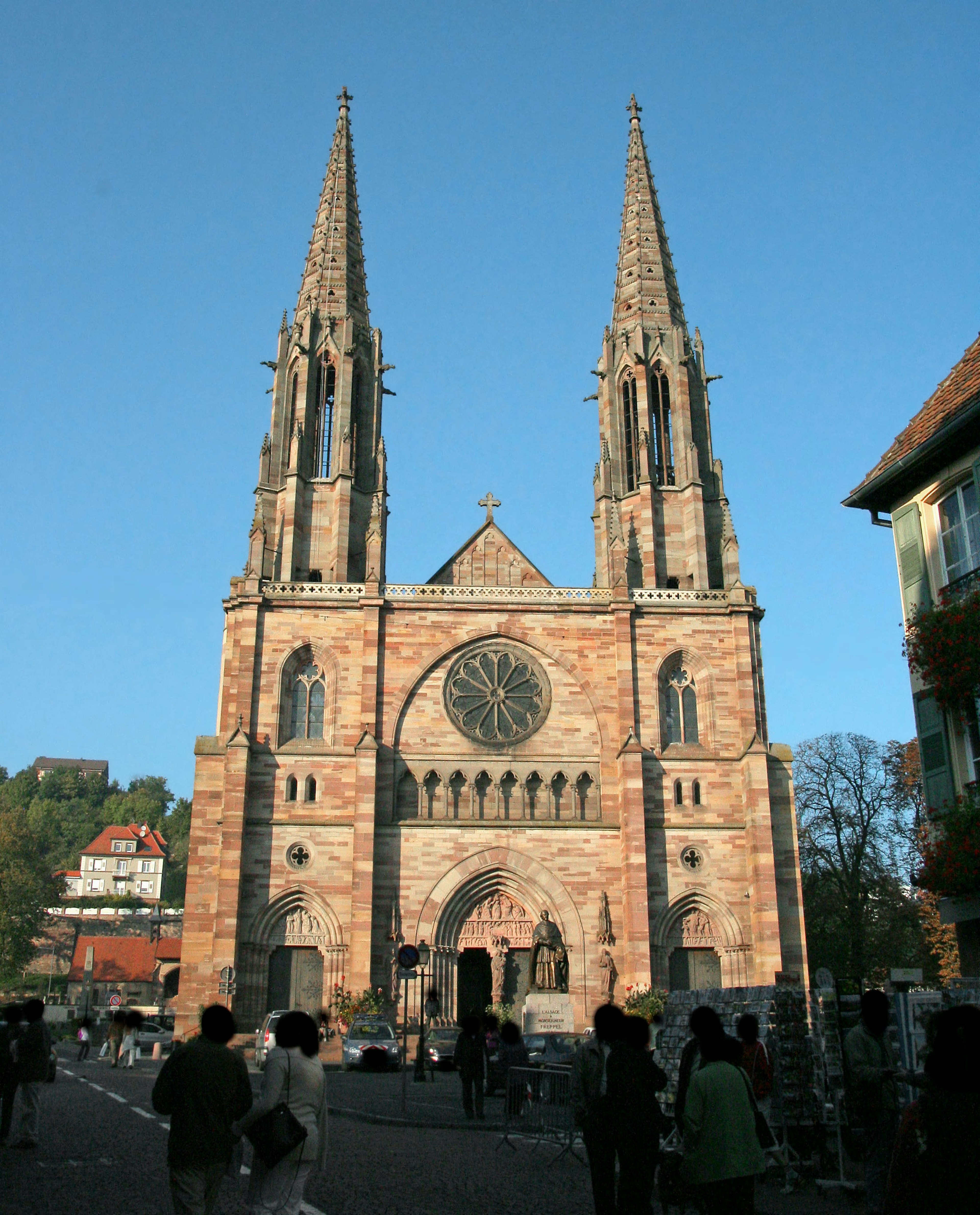 Esterno di una chiesa in pietra rossa con alte guglie e una grande rosa