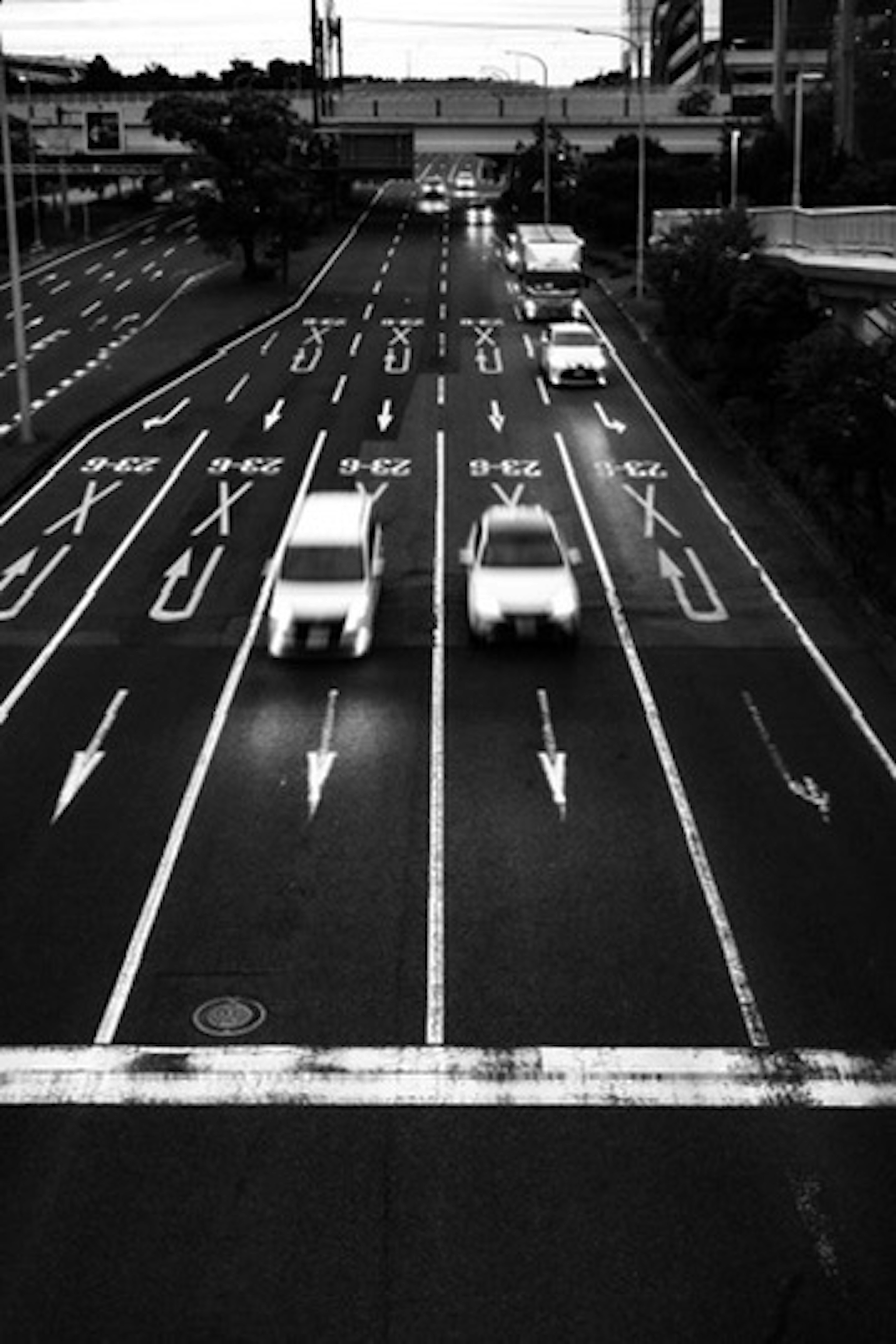 Schwarzweißbild von Fahrzeugen auf einer Straße mit Richtungspfeilen