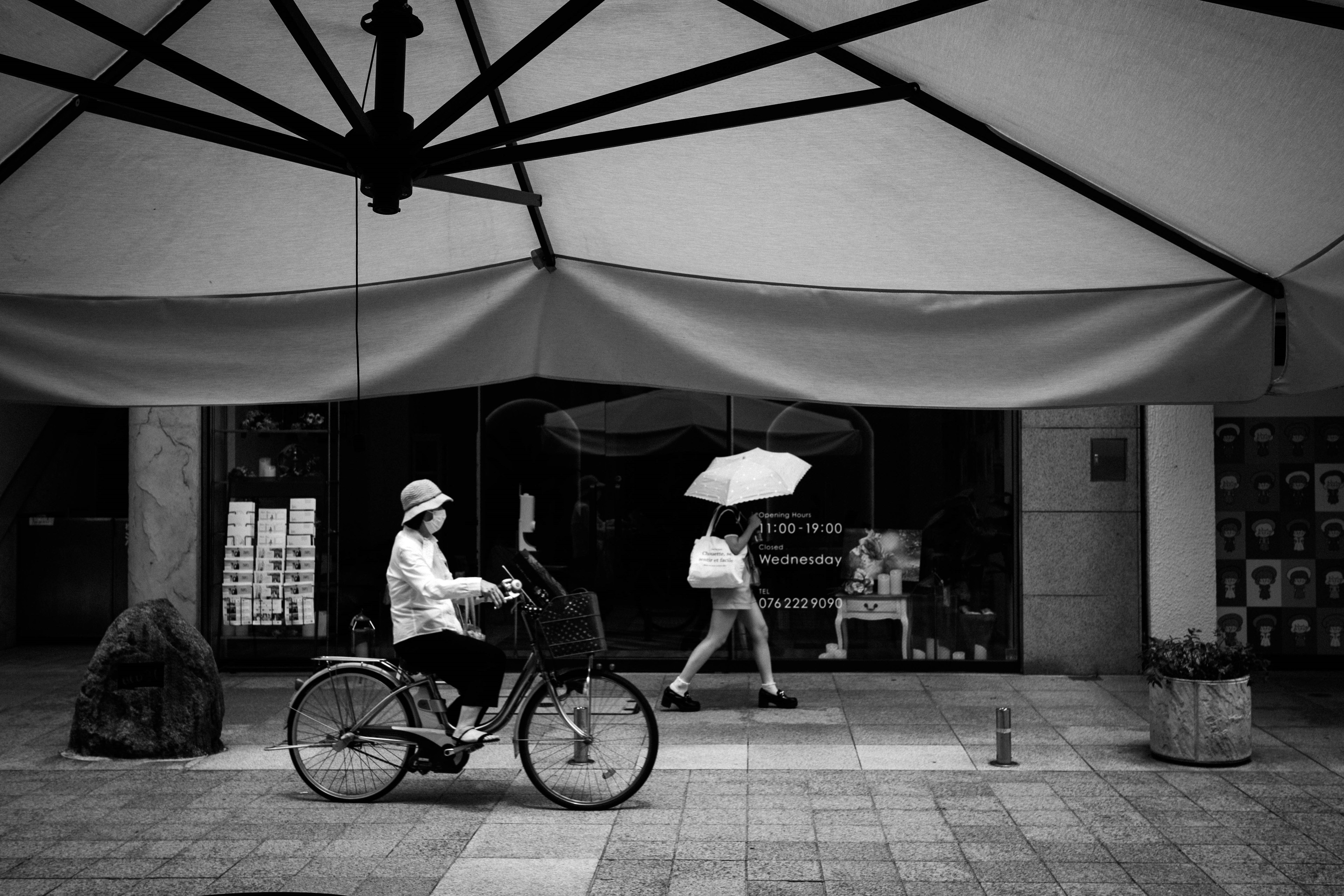 Une femme à vélo et une autre femme avec un parapluie dans une scène de rue