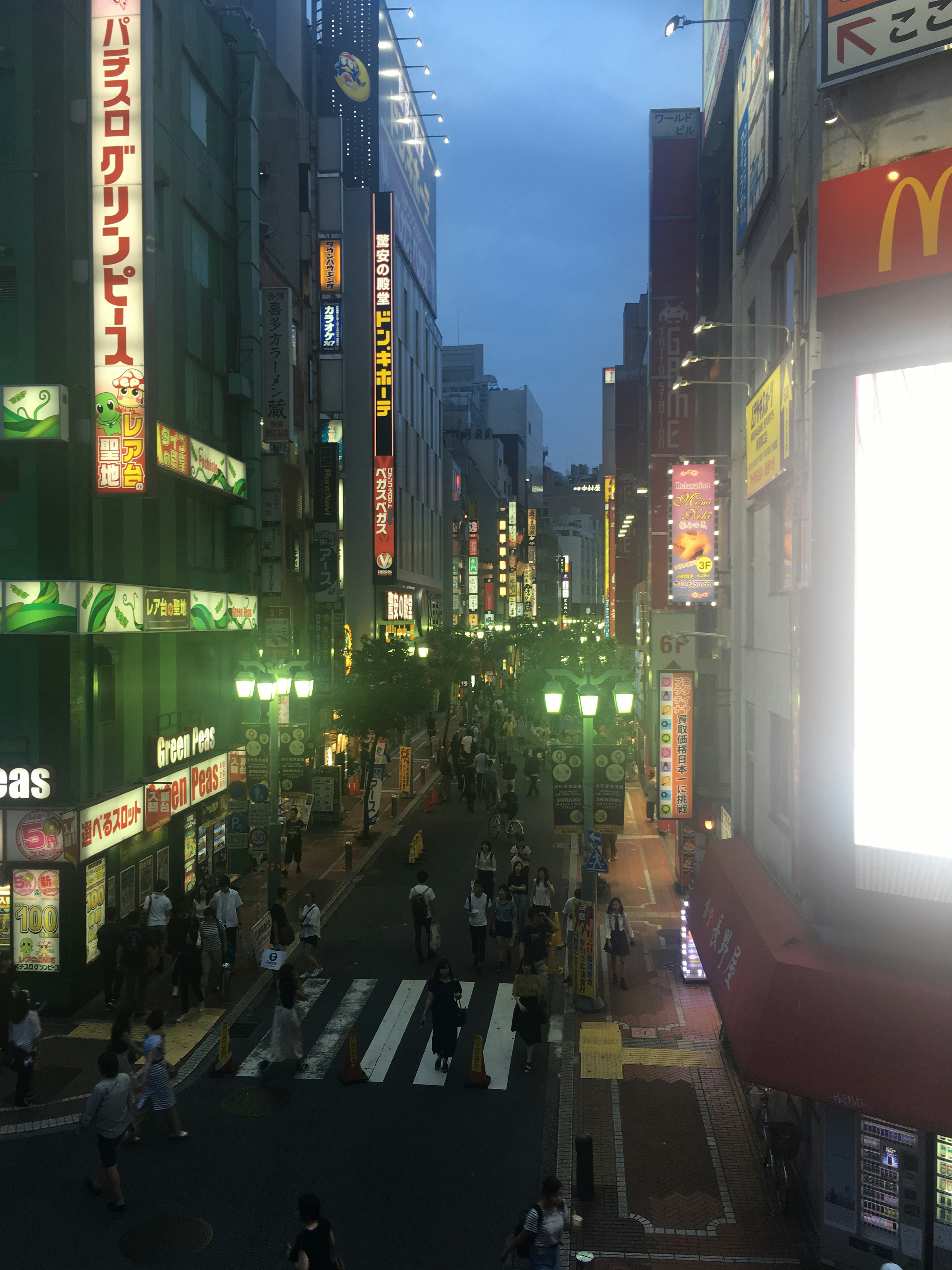 夜の繁華街に人々が行き交う様子 緑色の看板と明るいネオンが目立つ