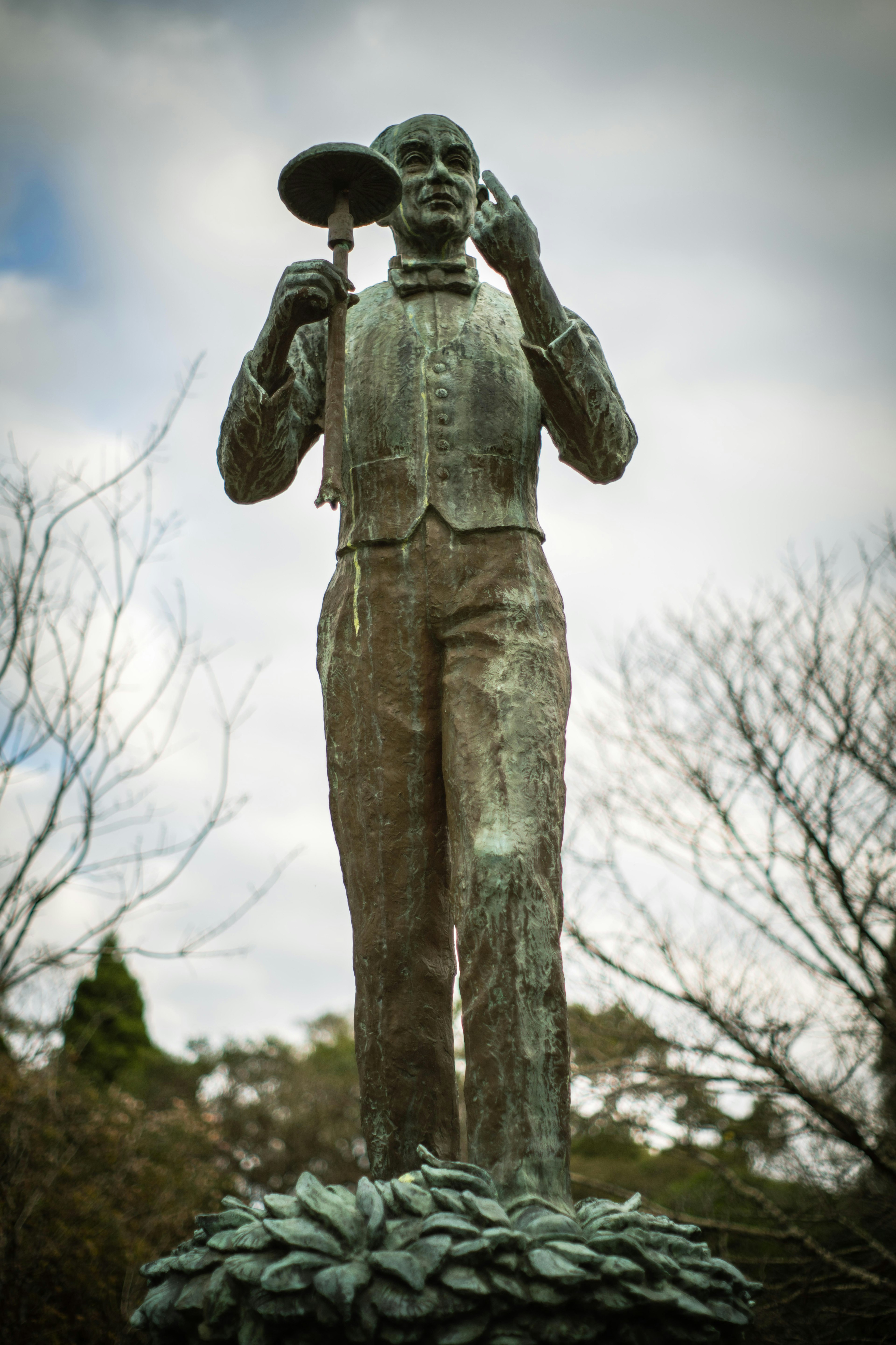 Statua di un uomo che tiene un piatto con alberi sullo sfondo