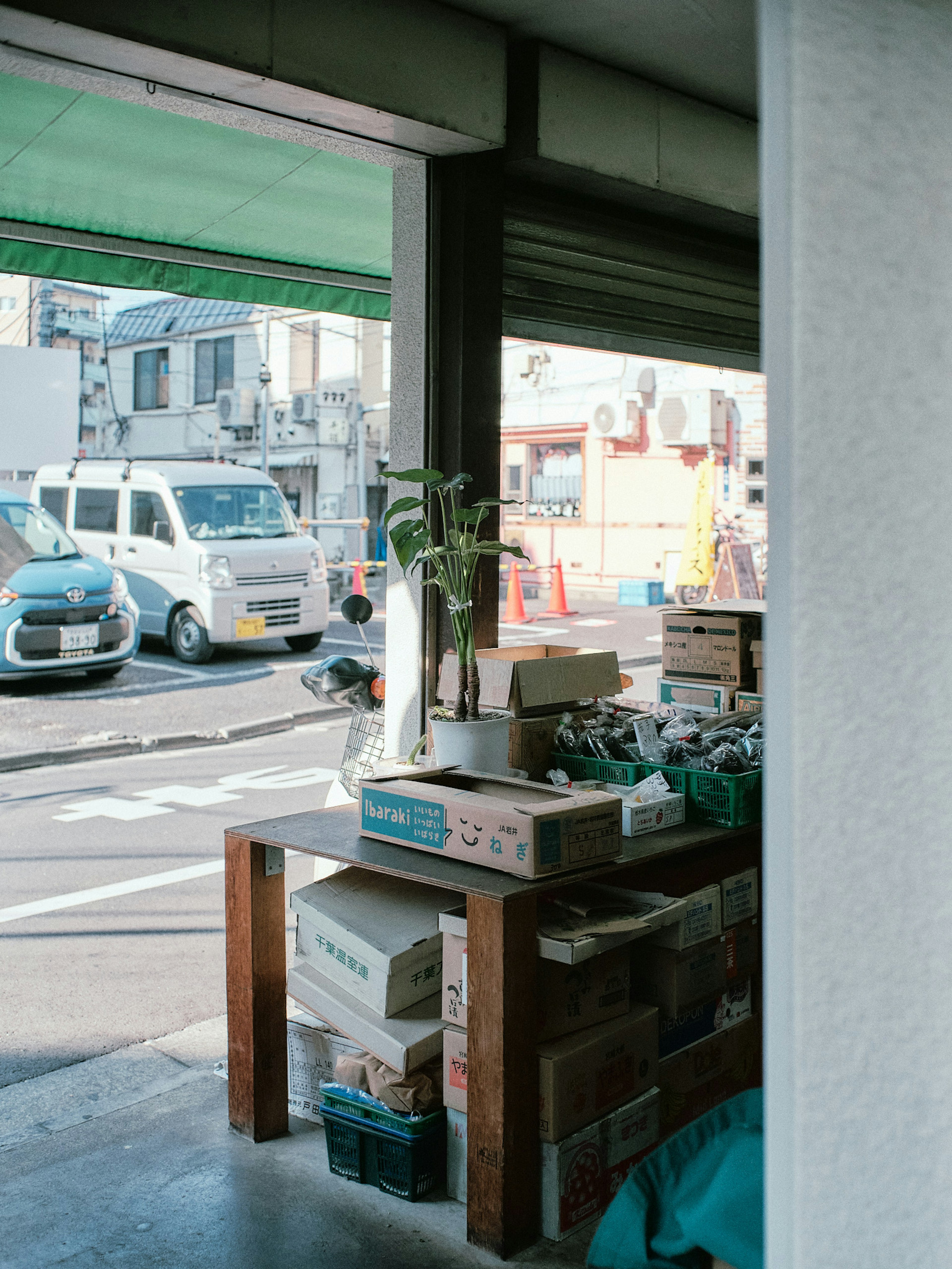 Table with boxes and a plant visible through an open entrance to the street