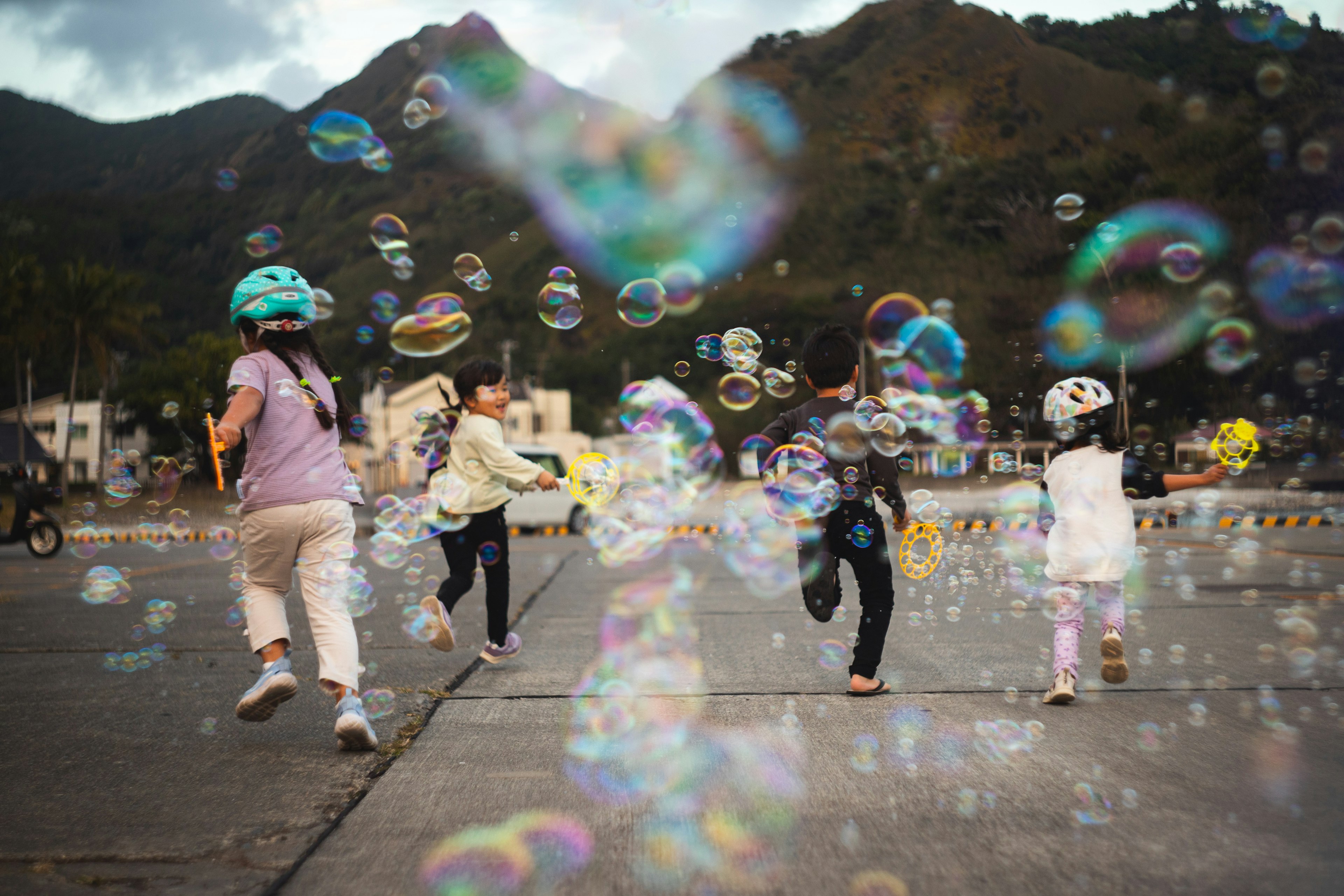 Children playing with bubbles on a road with a mountain background