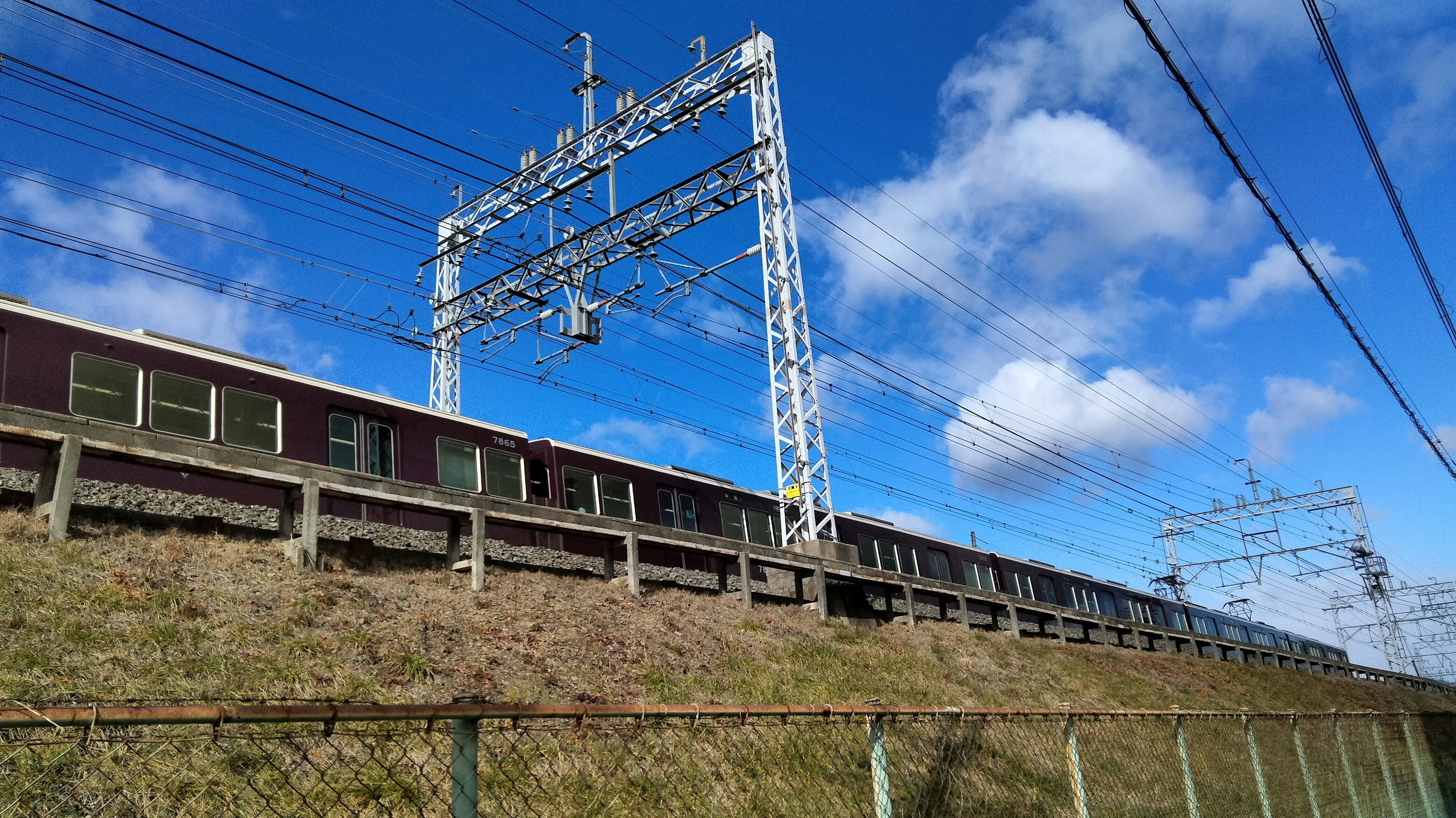 青空の下にある高架鉄道と電線の風景