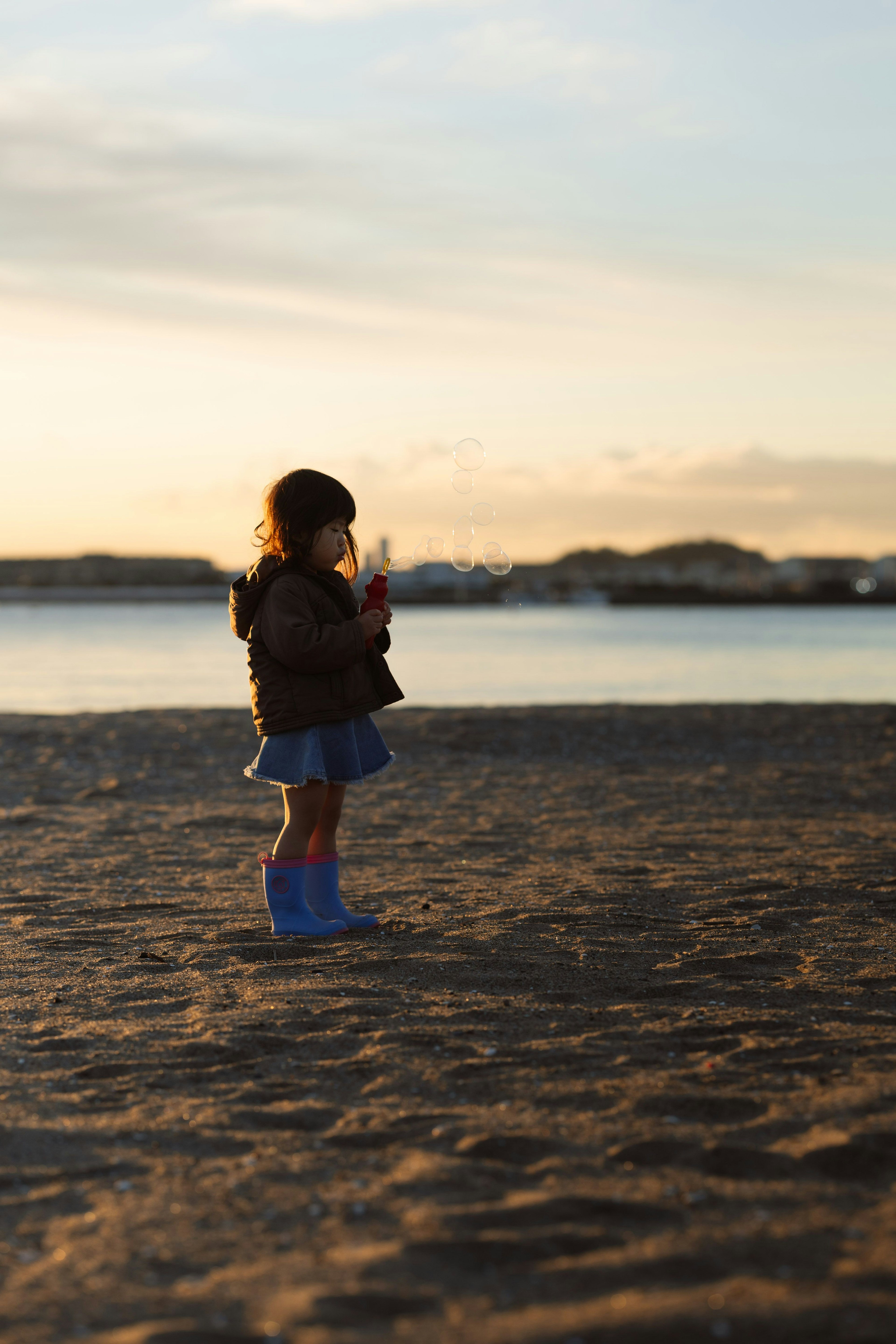 夕日を背景に立っている子供のシルエット 海岸の砂浜で遊んでいる