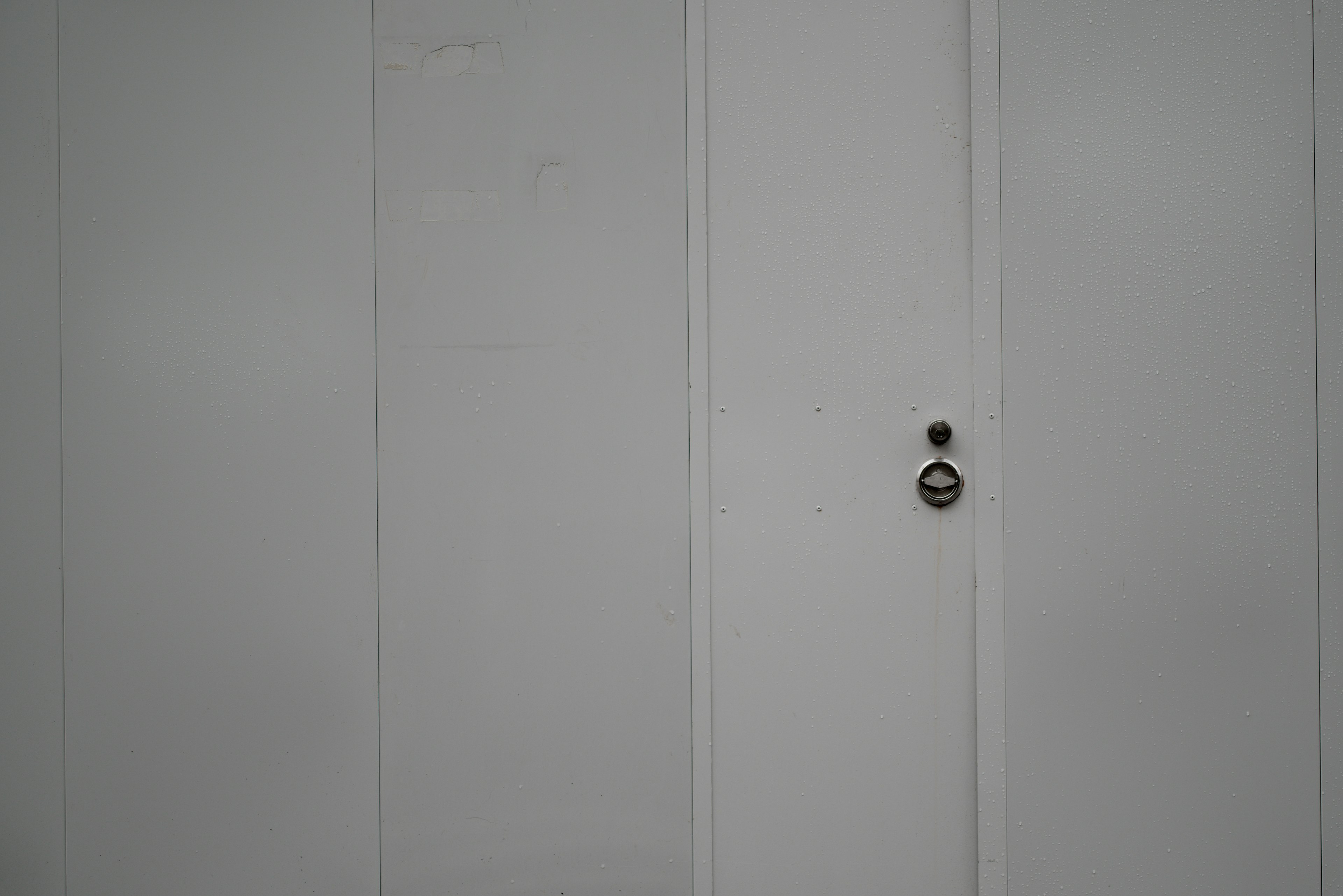 Close-up of a white door featuring a keyhole and doorknob in the center