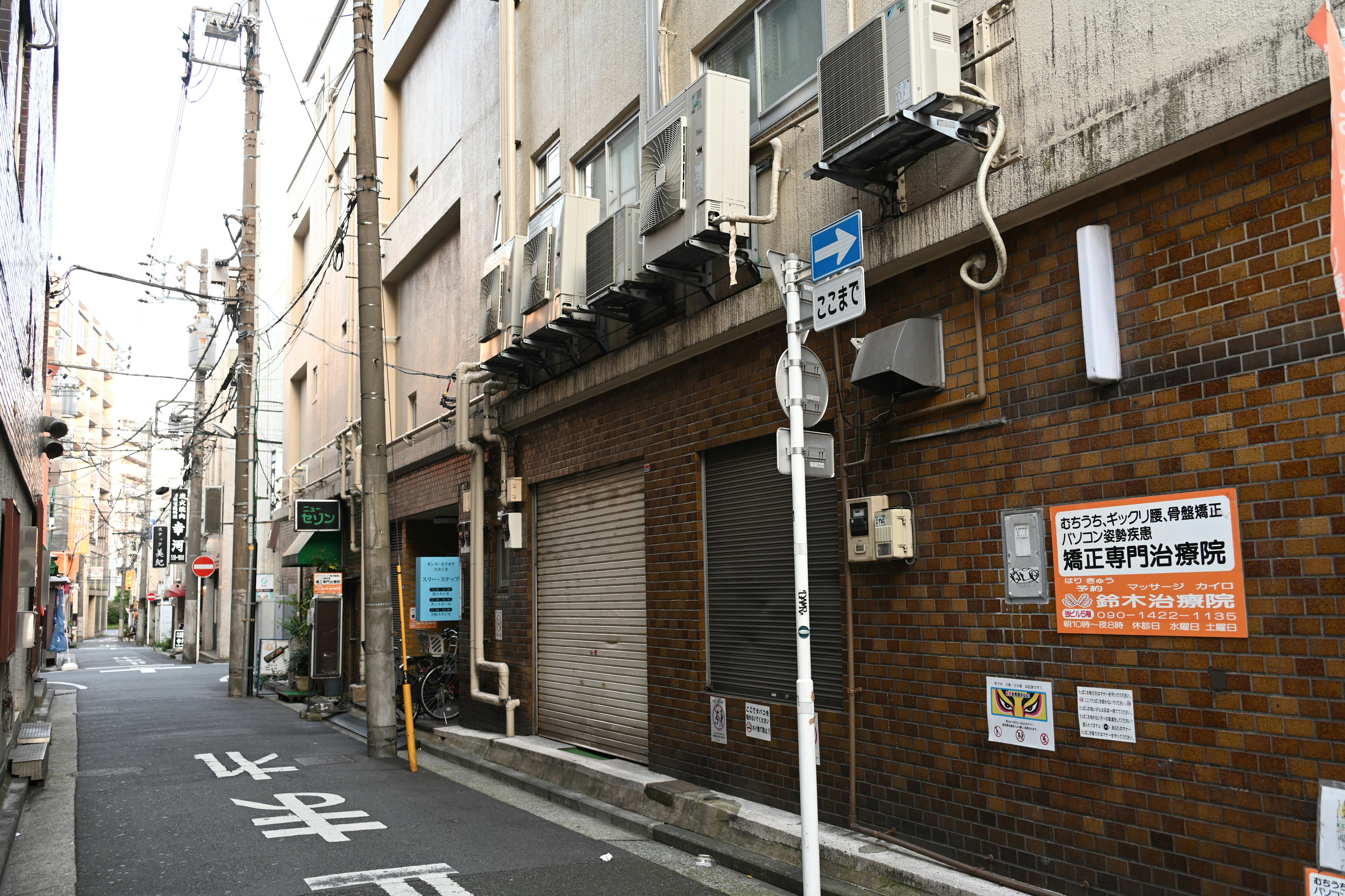 Schmale Gasse mit mehreren Gebäude-Fassaden und Beschilderung