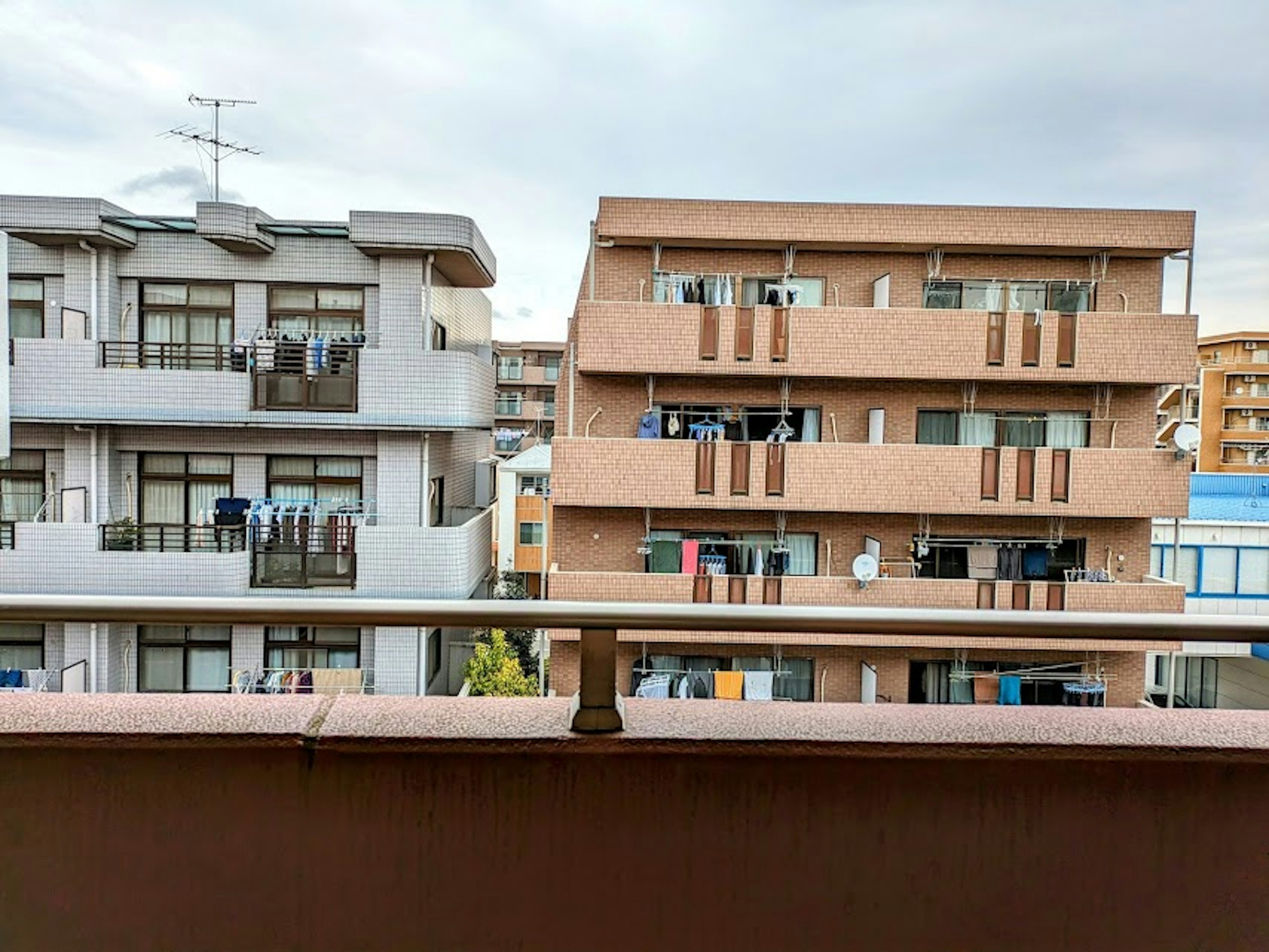 Vista desde un balcón que muestra edificios de apartamentos con ropa colgada bajo un cielo gris