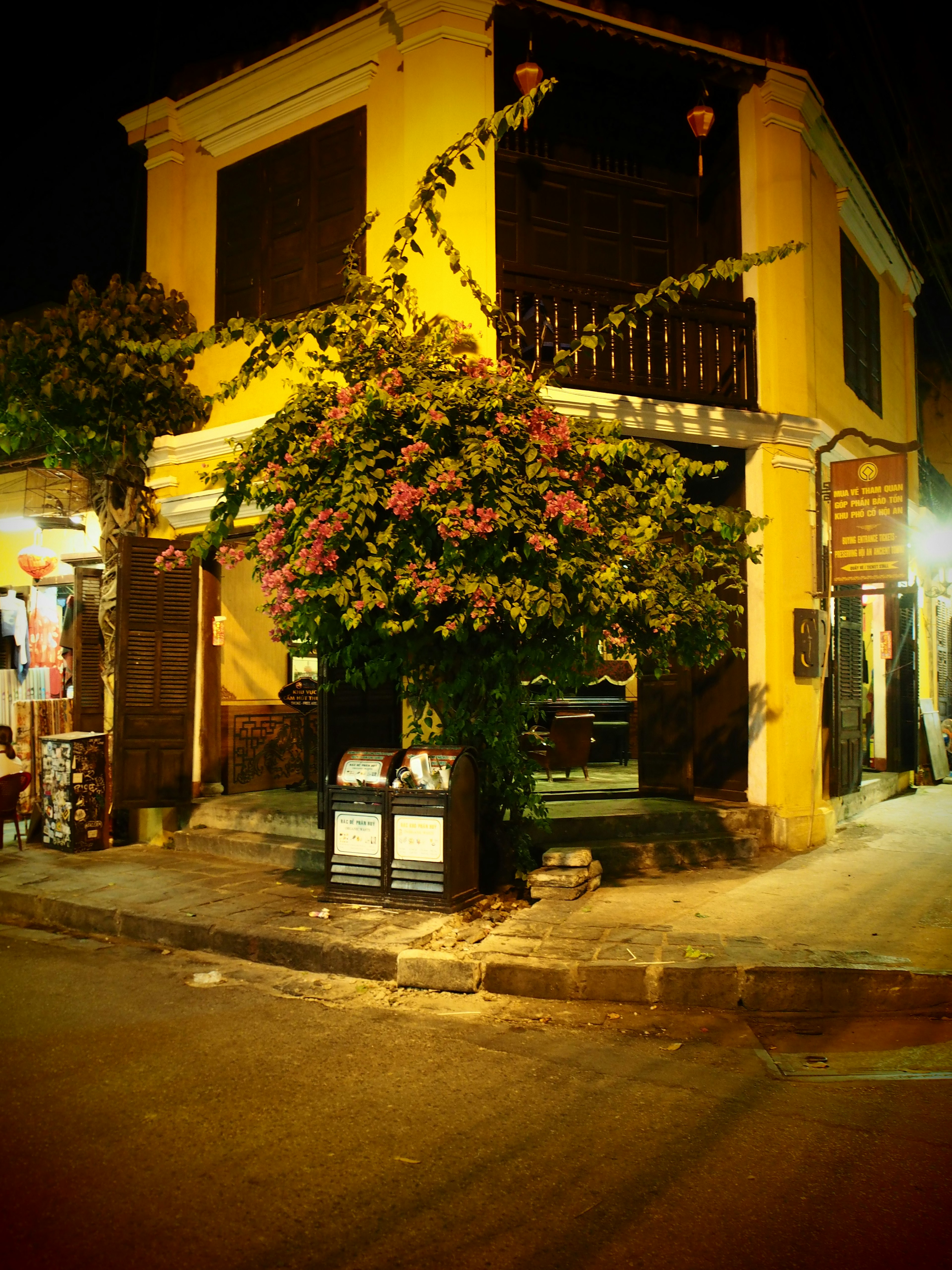 A yellow building at a street corner with vibrant flowering plants