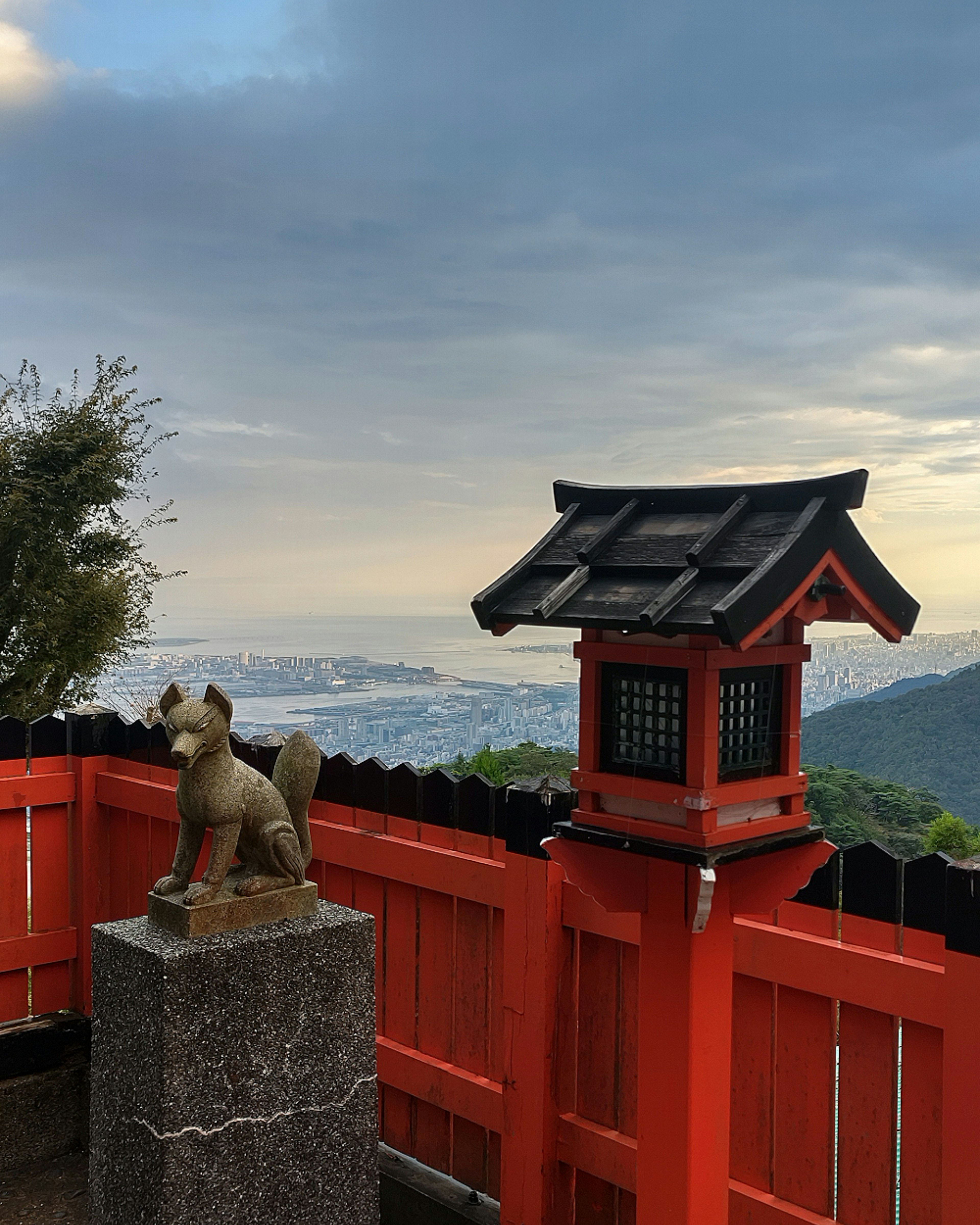 赤いフェンスのある景色と狐の像がある風景