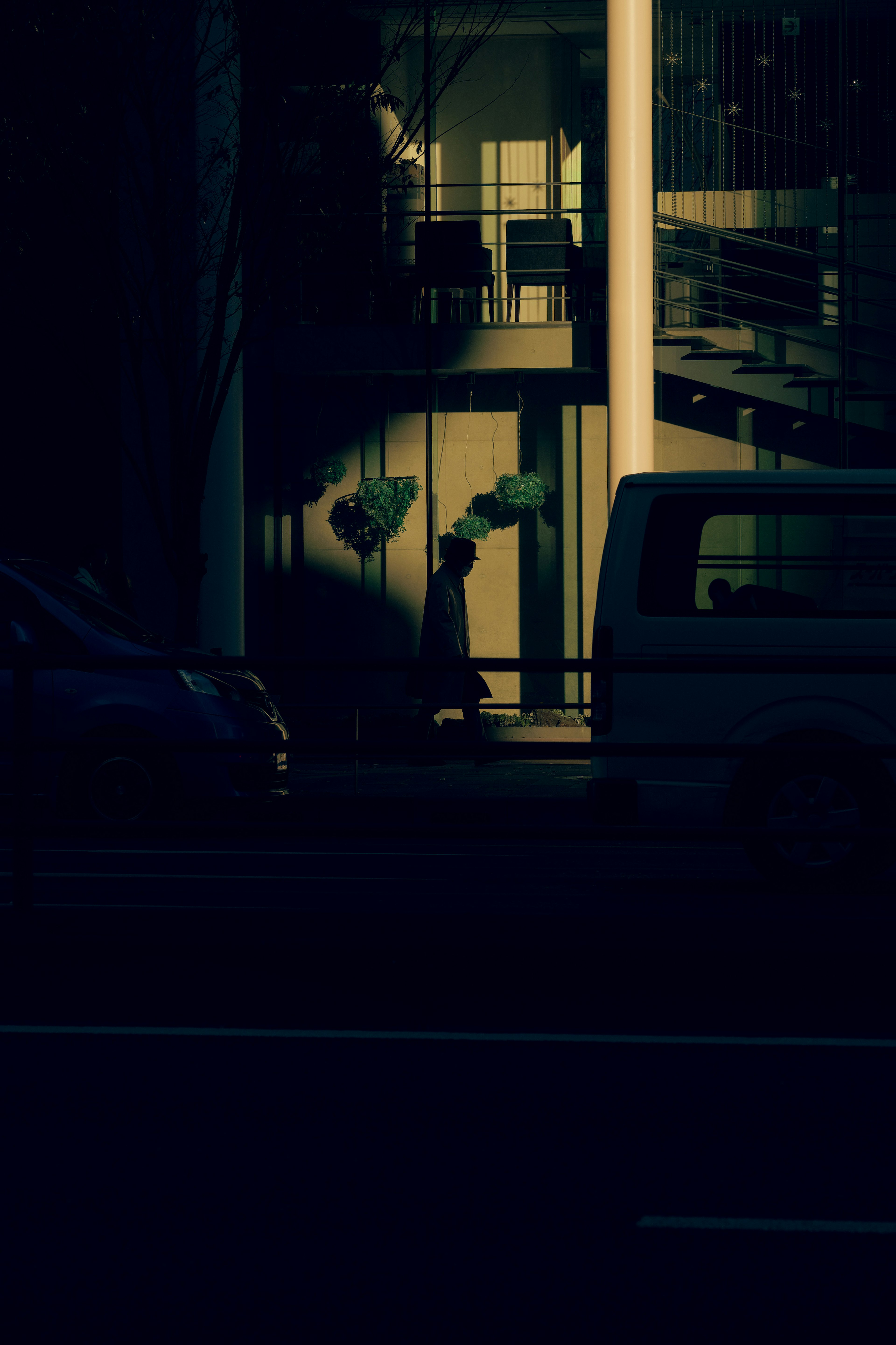 Silhouetted figure in a dark street scene with bright building windows