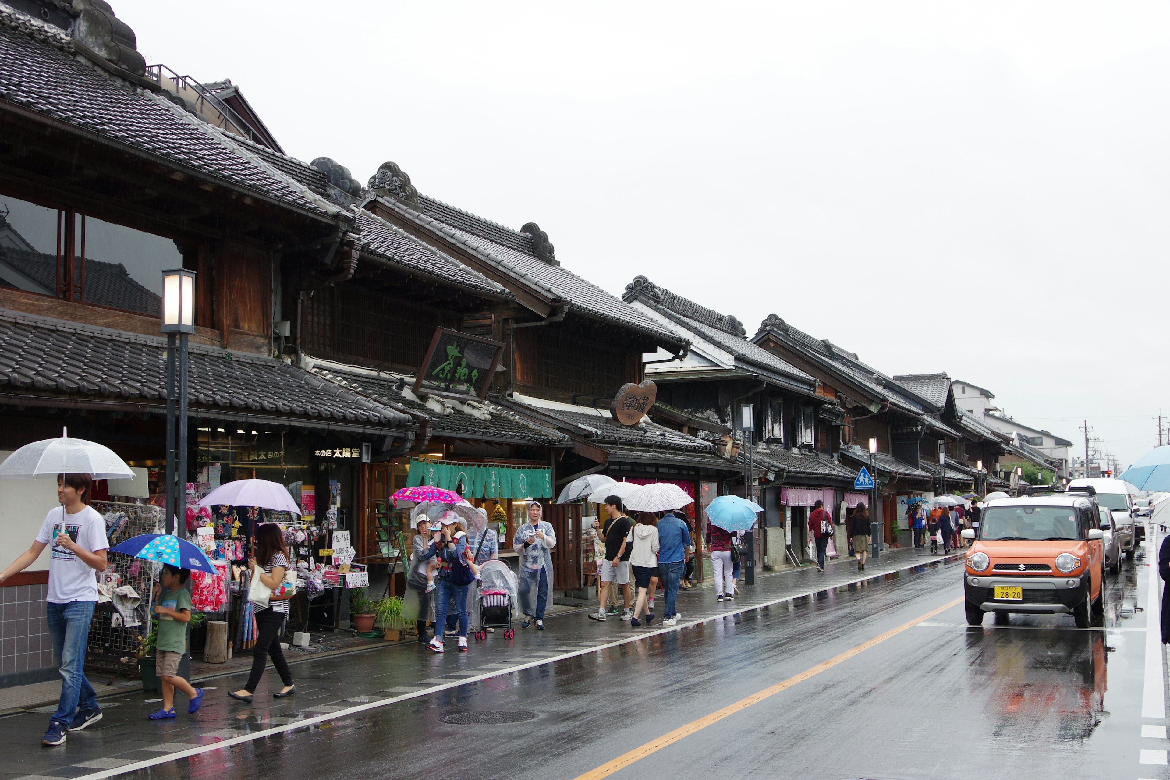 雨の中の伝統的な日本の街並みと傘をさした人々