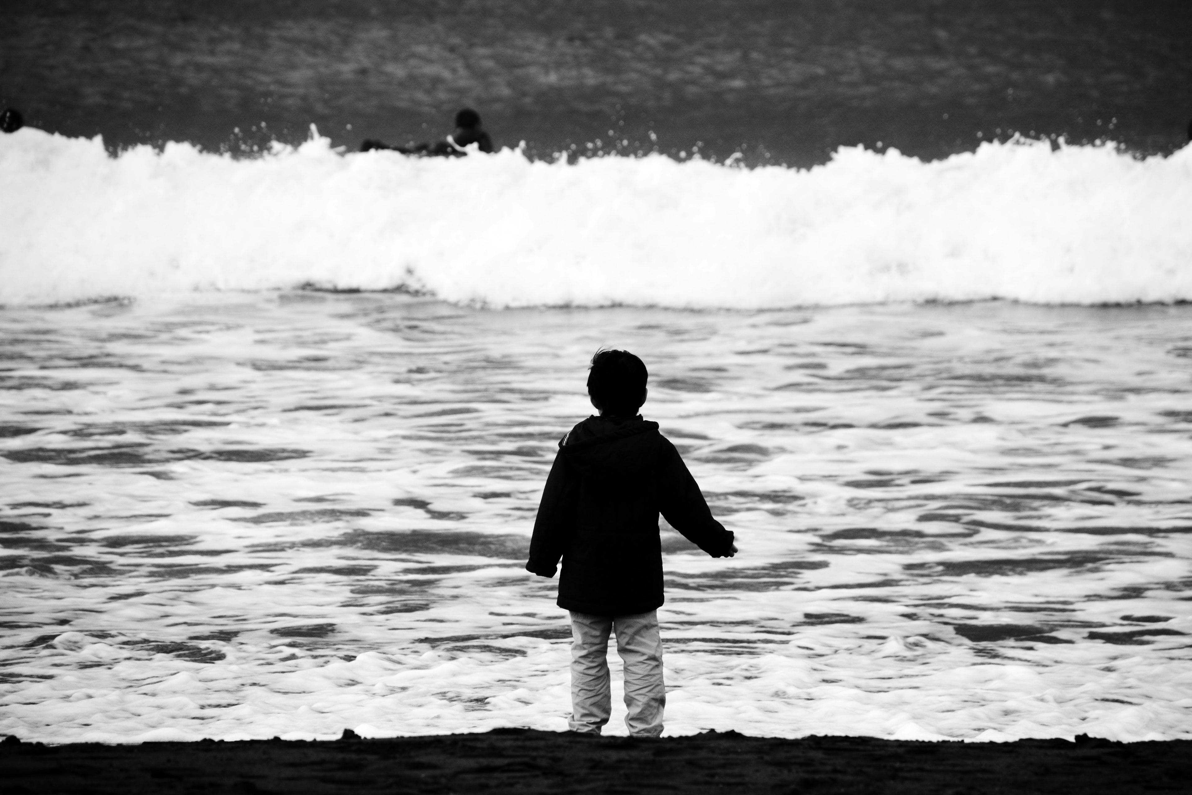 海辺で波を見つめる子供のシルエット