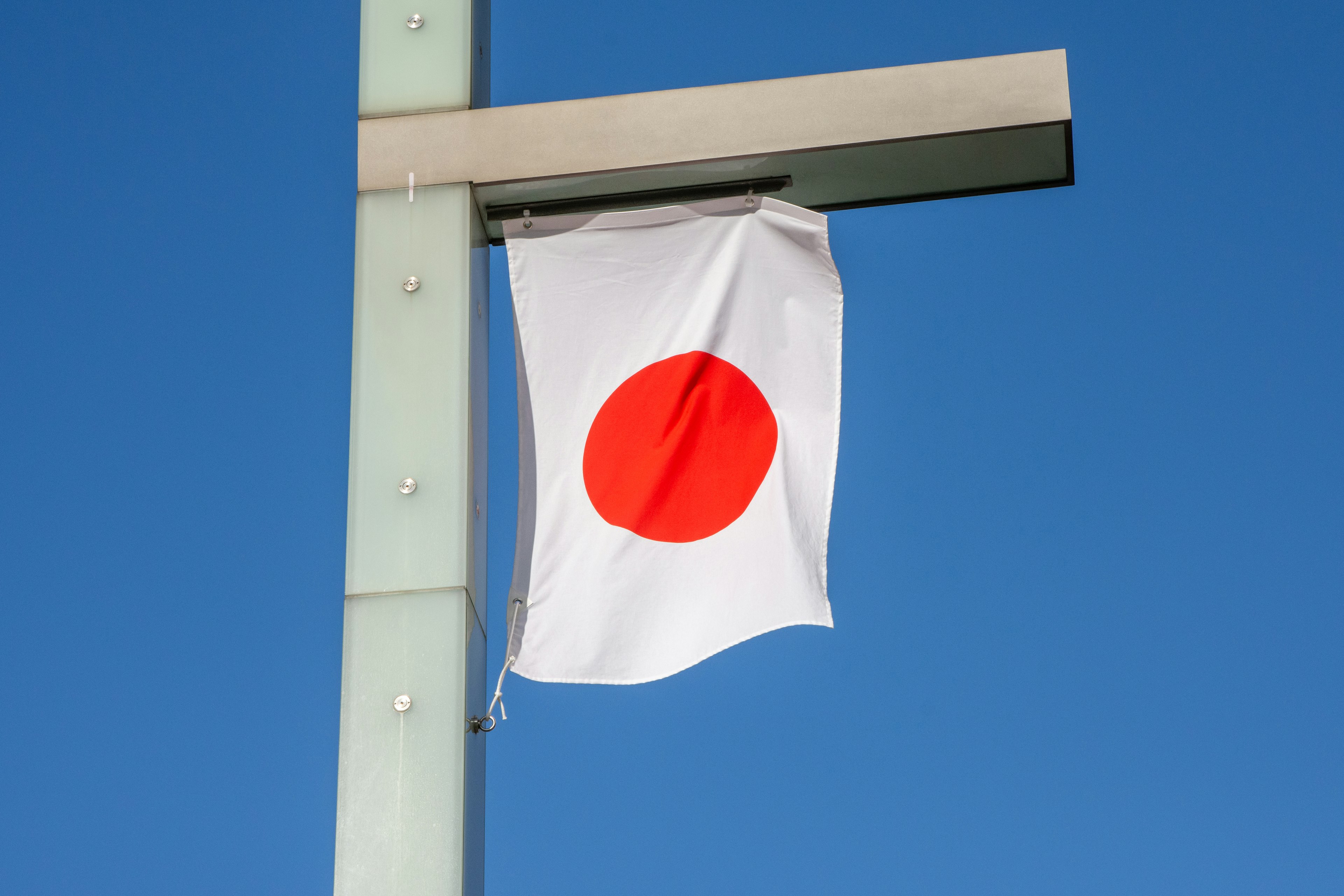 Bendera nasional Jepang yang dipajang di bawah langit biru dengan lingkaran merah di atas latar putih