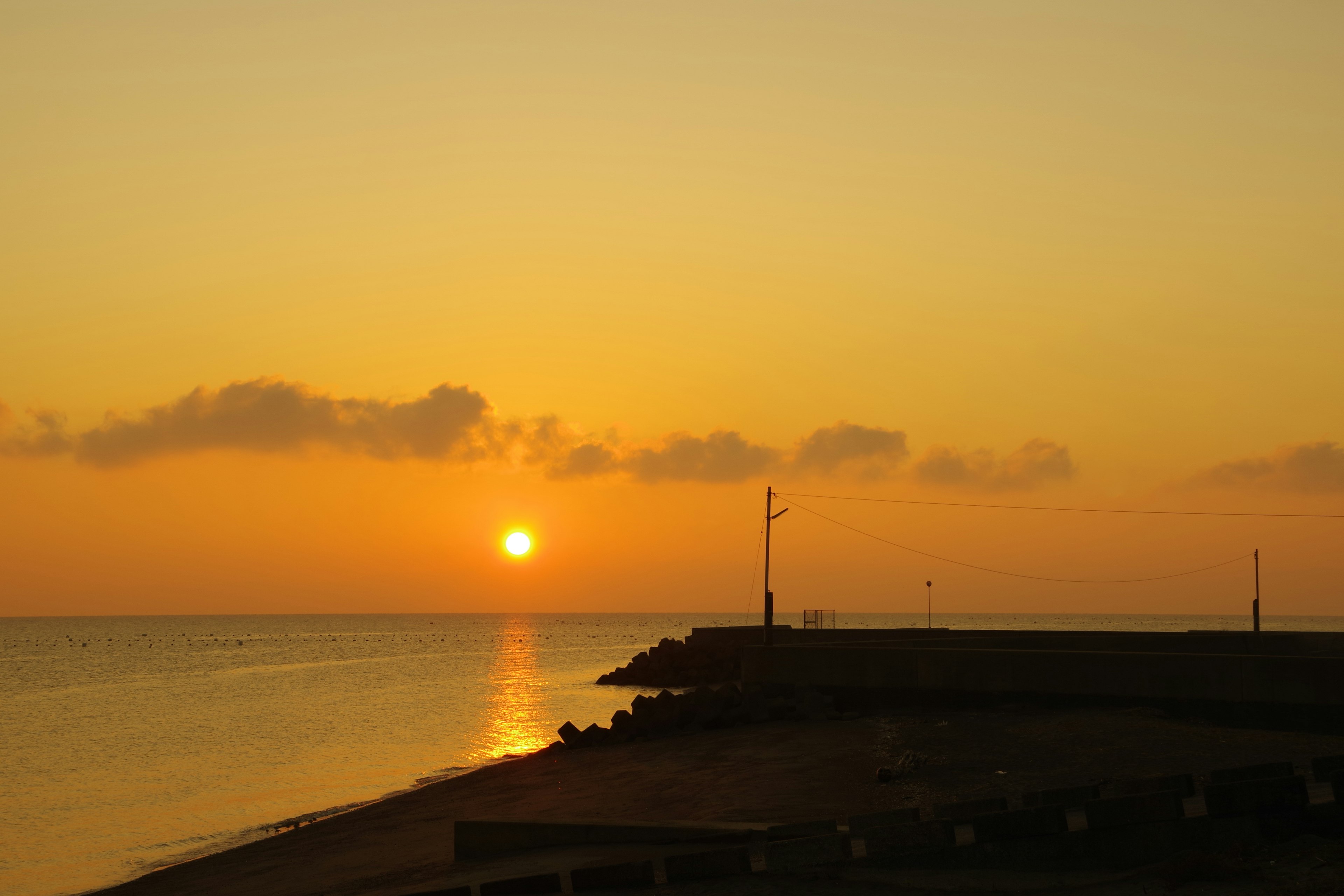 Coucher de soleil orange sur la mer avec silhouettes d'un quai