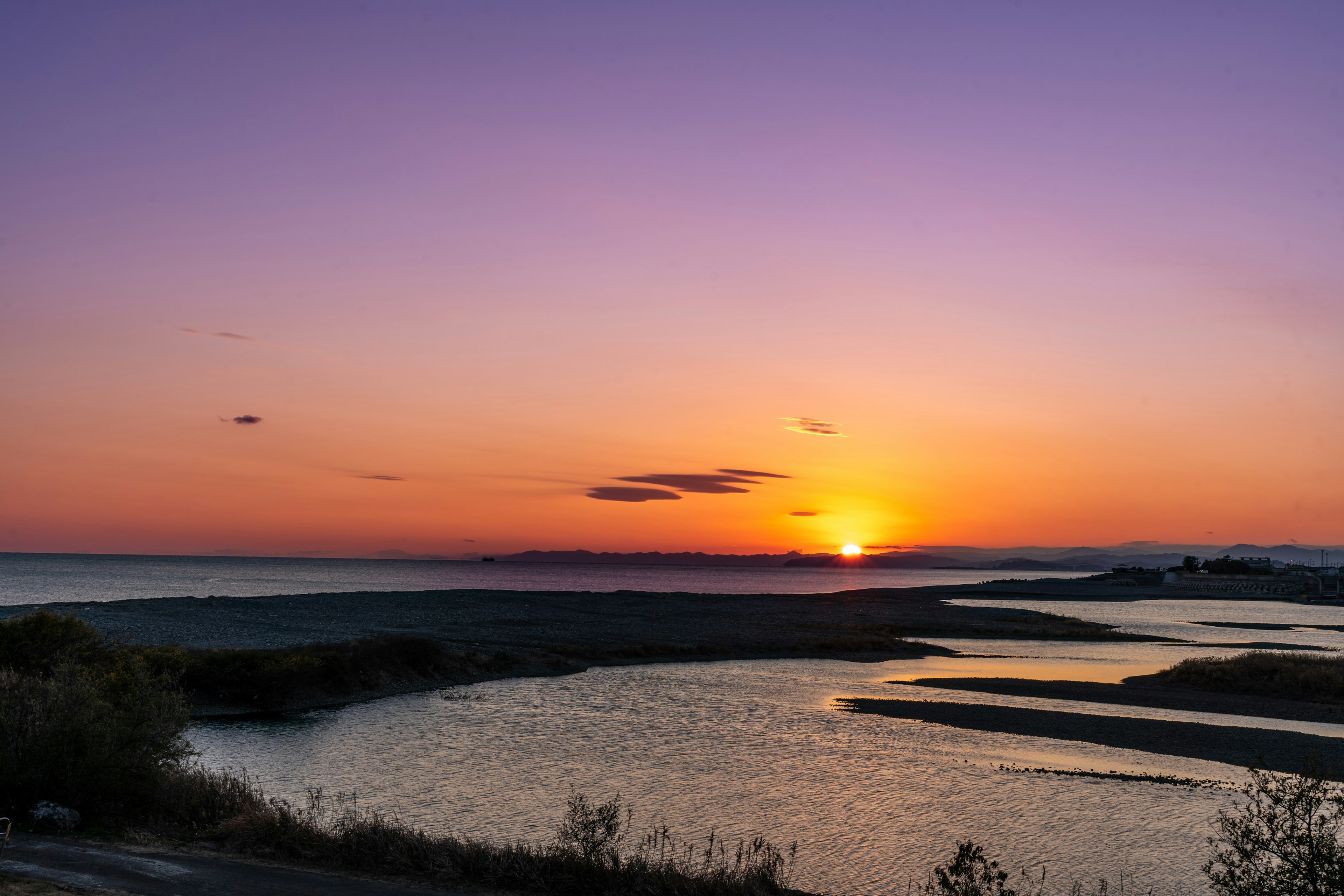 美しい夕日が沈む海と川の景色