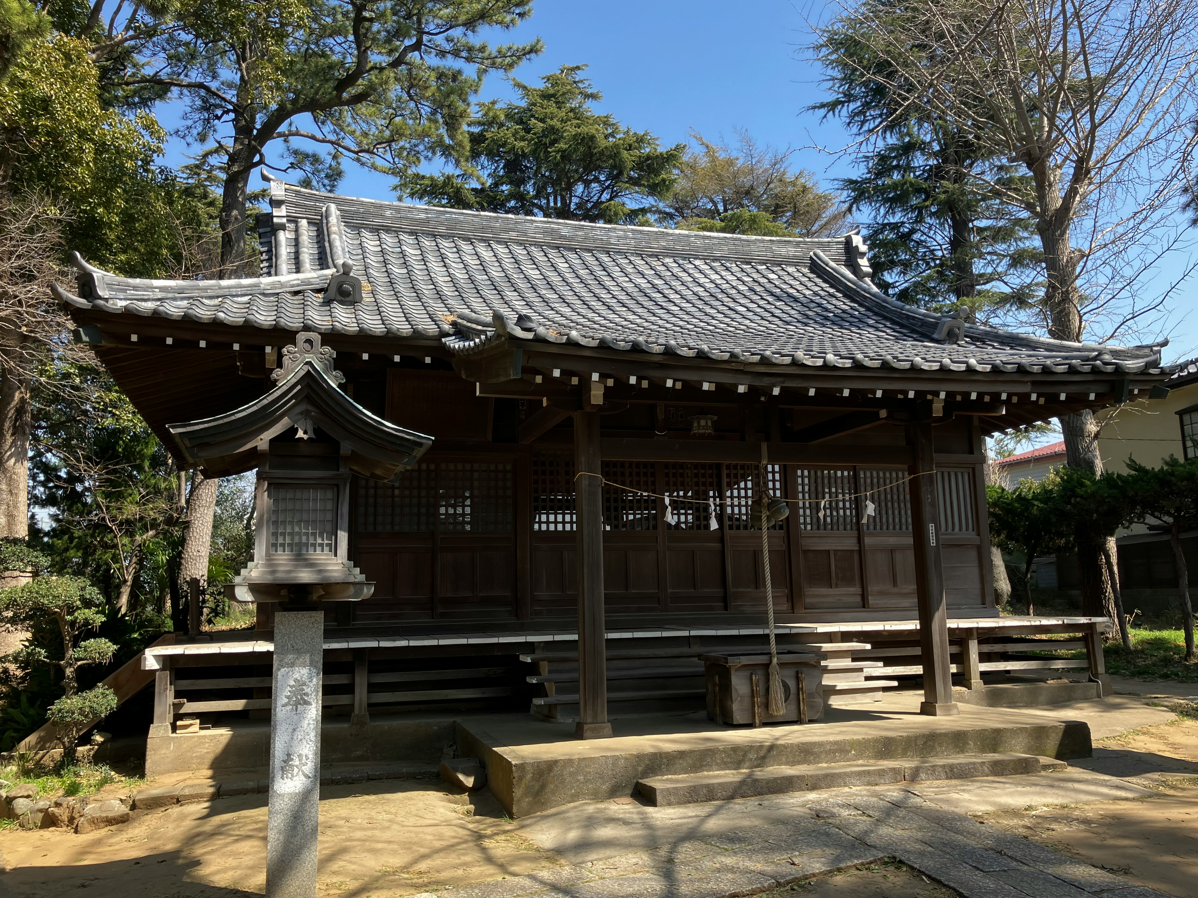 Traditional Japanese temple exterior with wooden structure and tiled roof surrounded by green trees