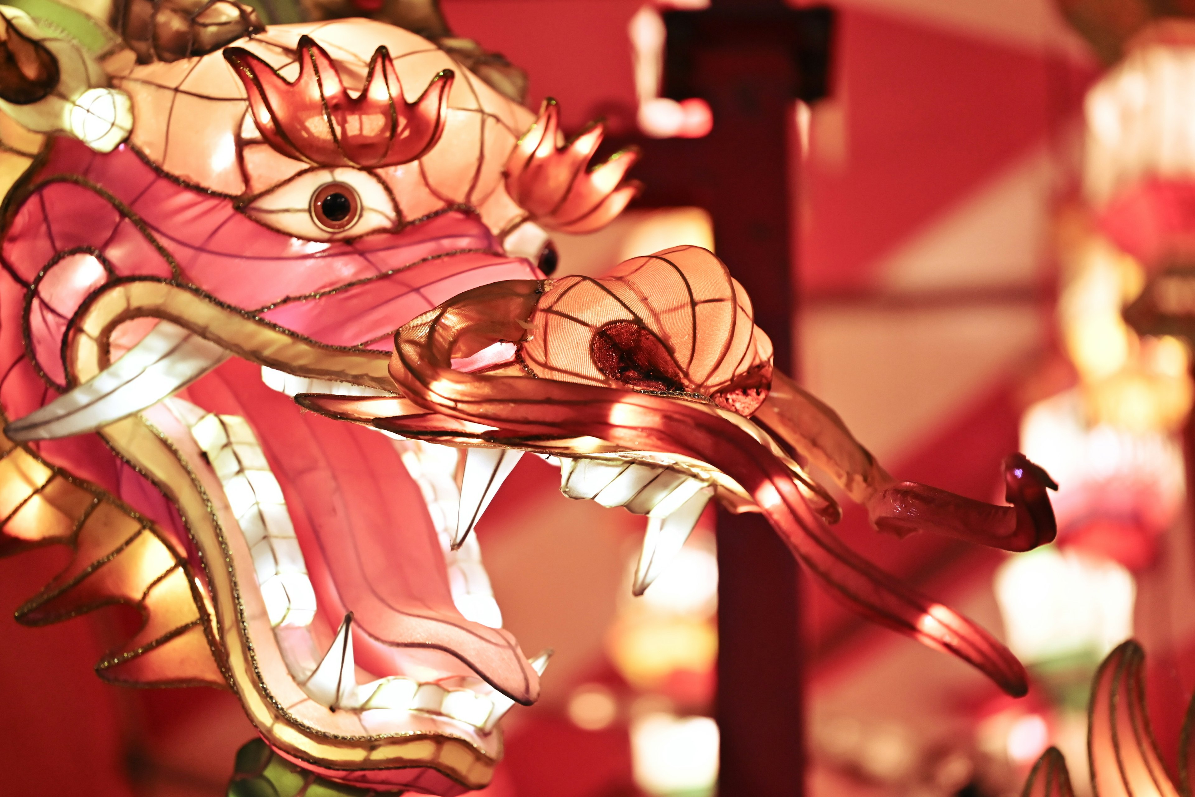 Close-up of a dragon lantern with glowing eyes and mouth surrounded by colorful lanterns