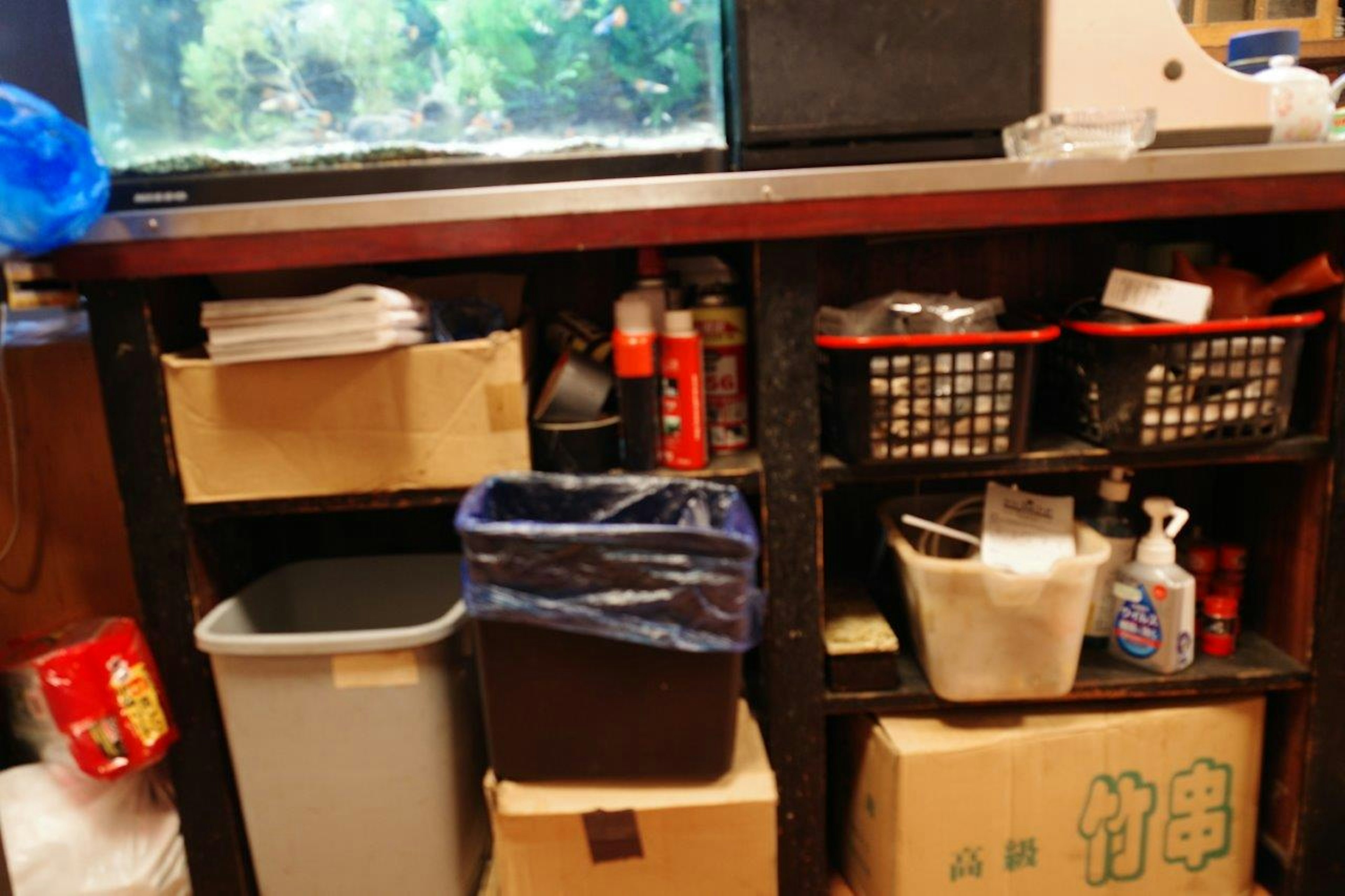 Foreground of a storage shelf with an aquarium Various storage boxes and a trash can are arranged