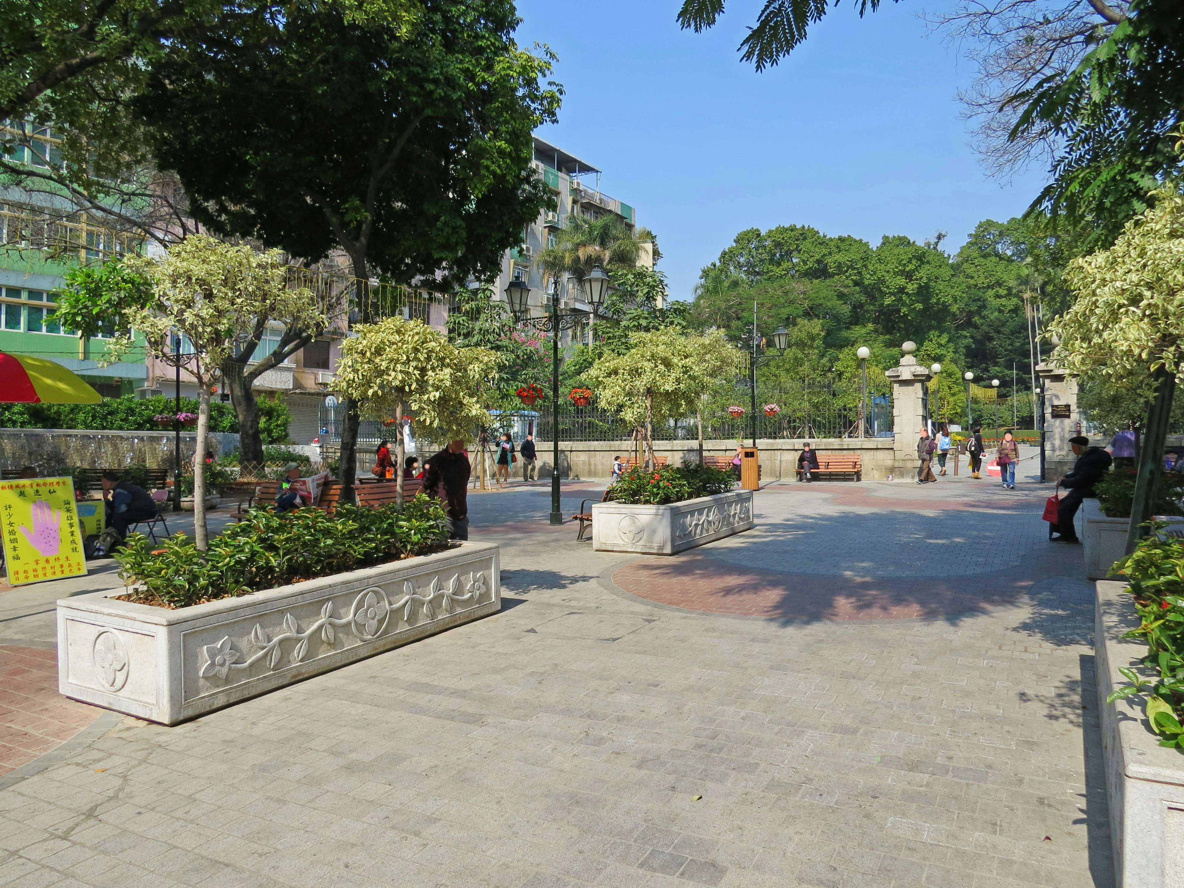 Escena de parque brillante con árboles verdes y flores, peatones presentes