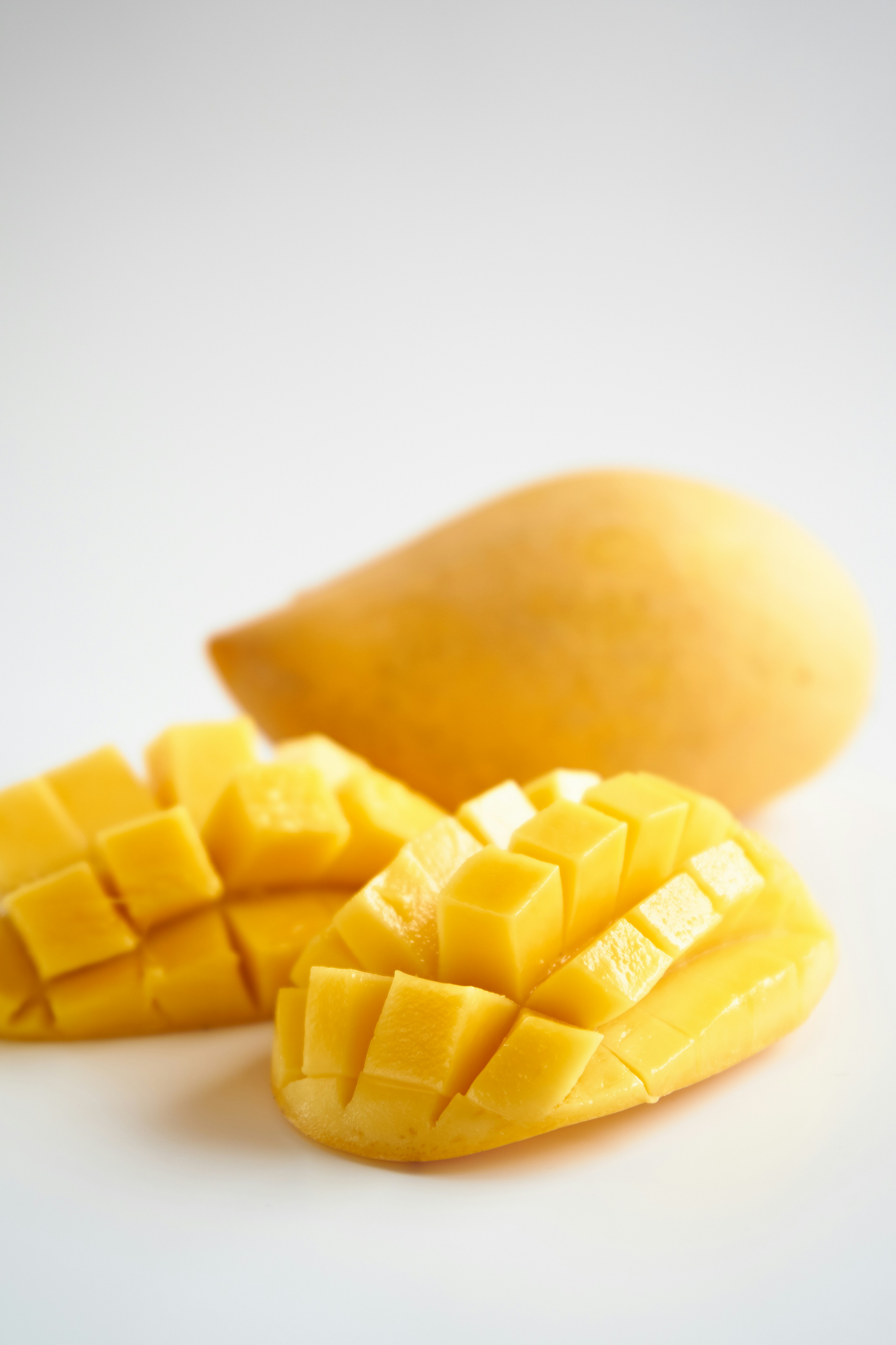 Lebendige gelbe Mango mit geschnittenen Stücken auf einem weißen Hintergrund