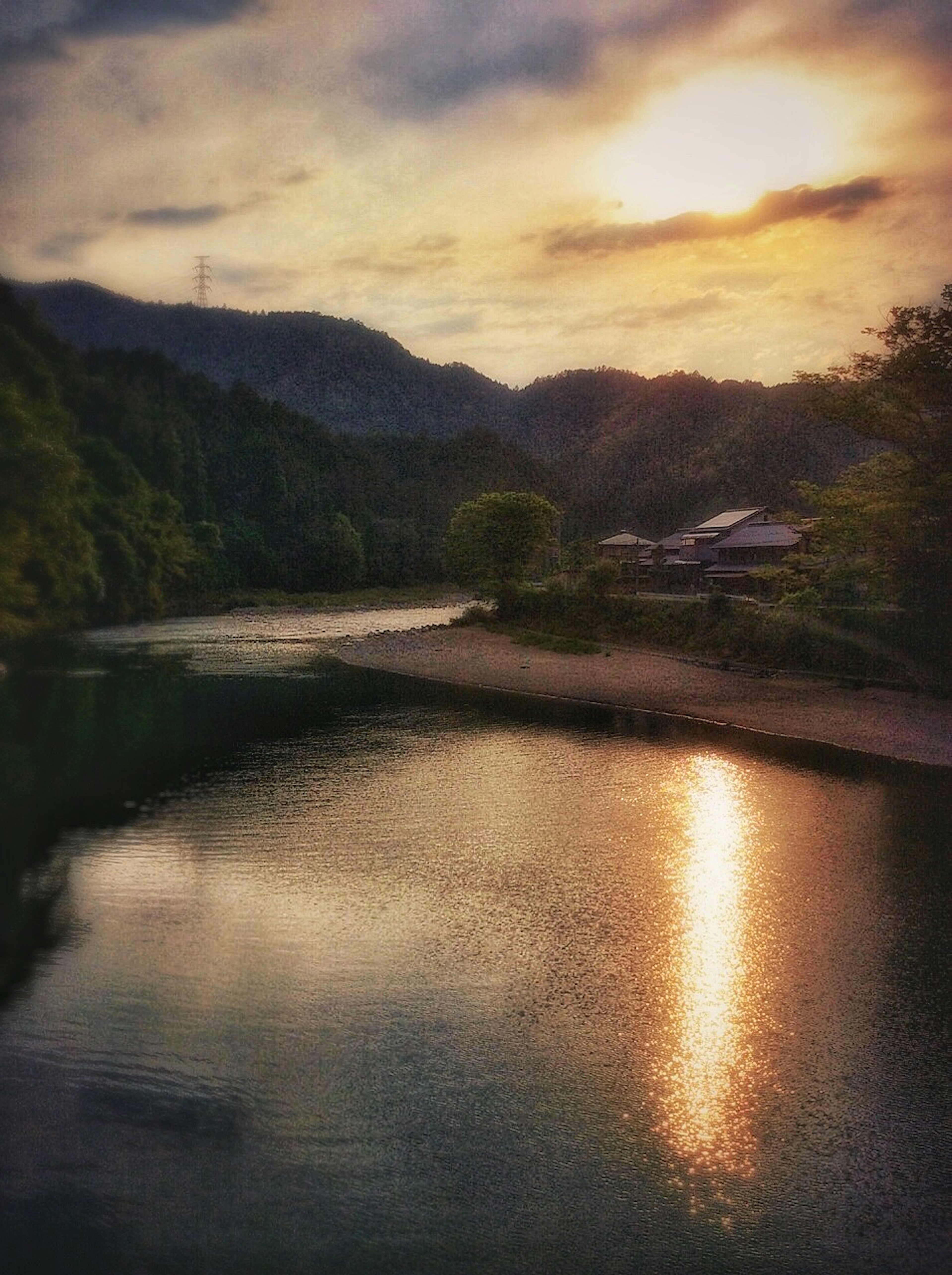 Paisaje sereno de un río con reflejos del atardecer y montañas