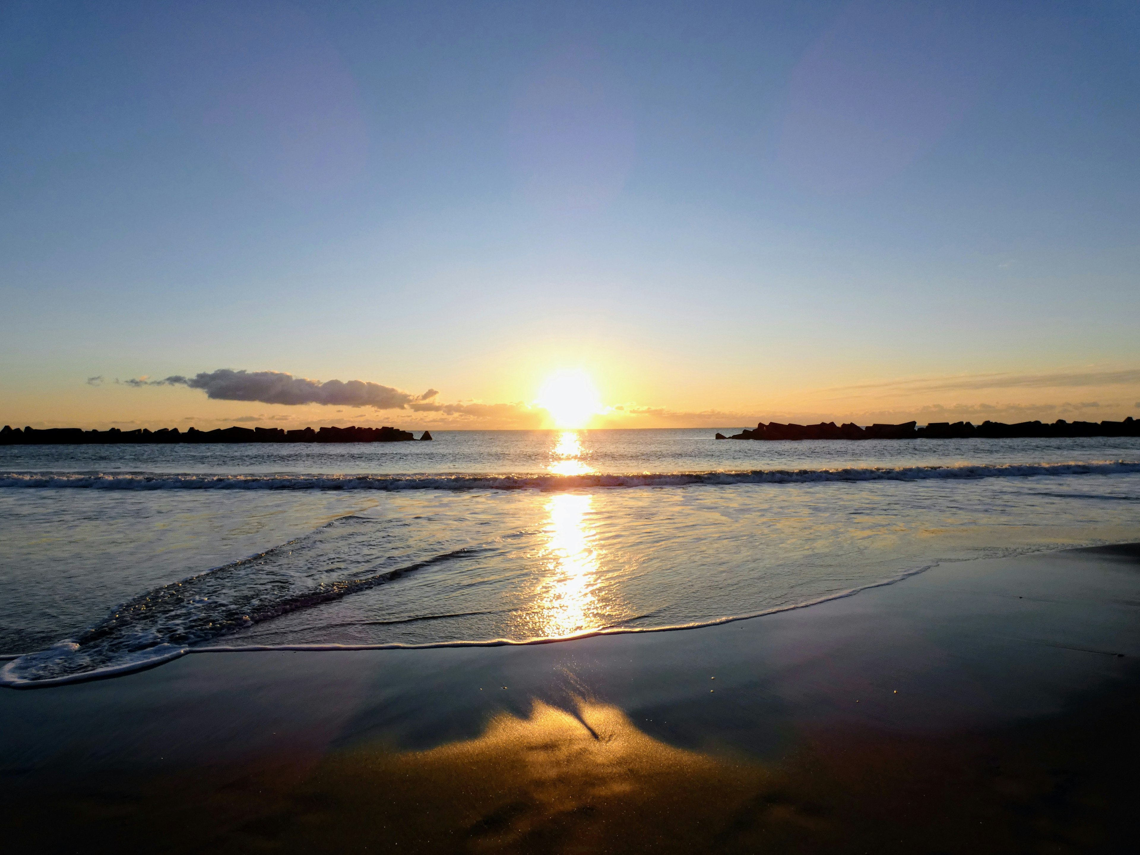 Malerscher Sonnenuntergang über dem Ozean mit sanften Wellen am Strand