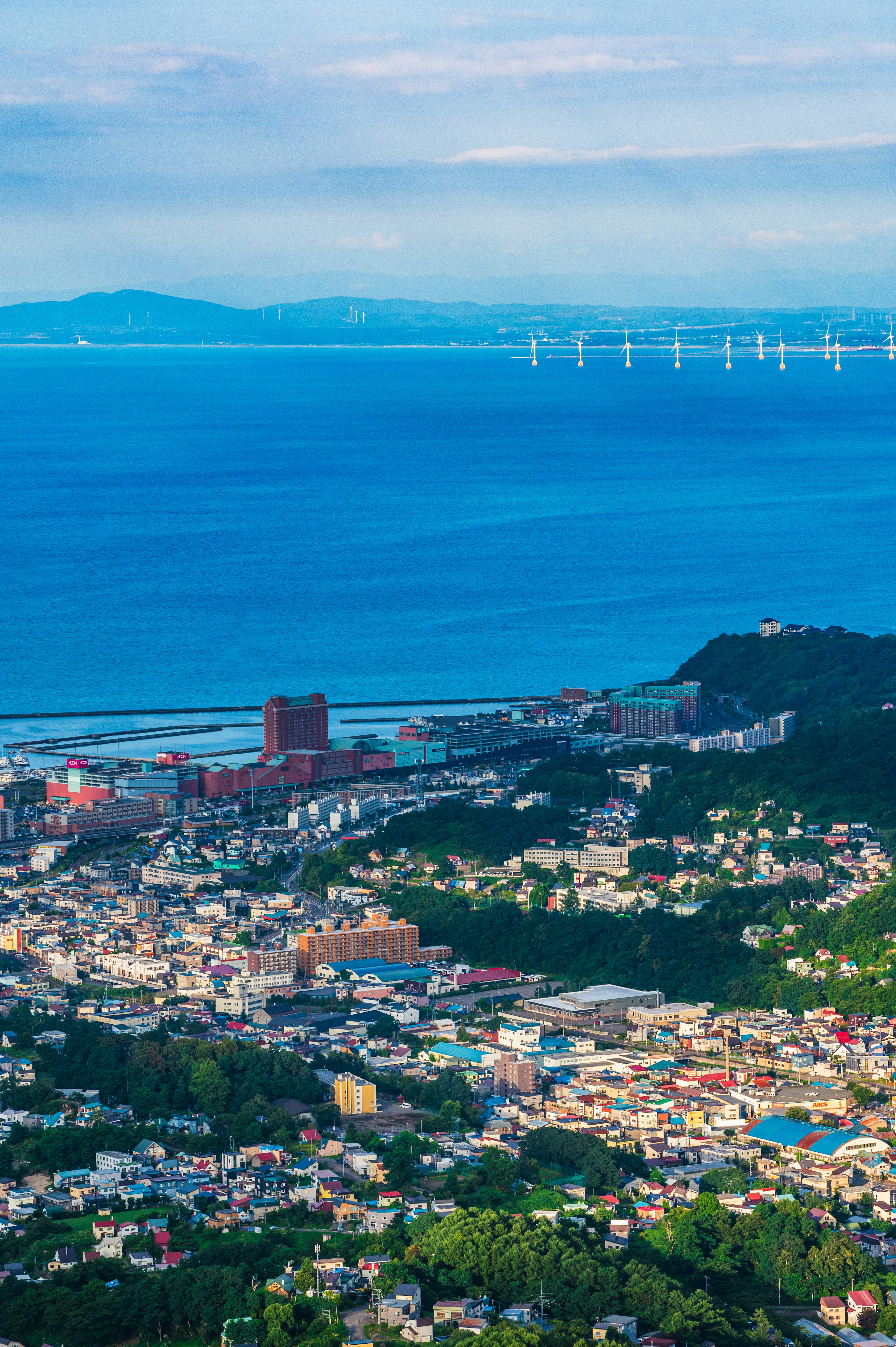 城市景觀，背景有海洋和風力發電機