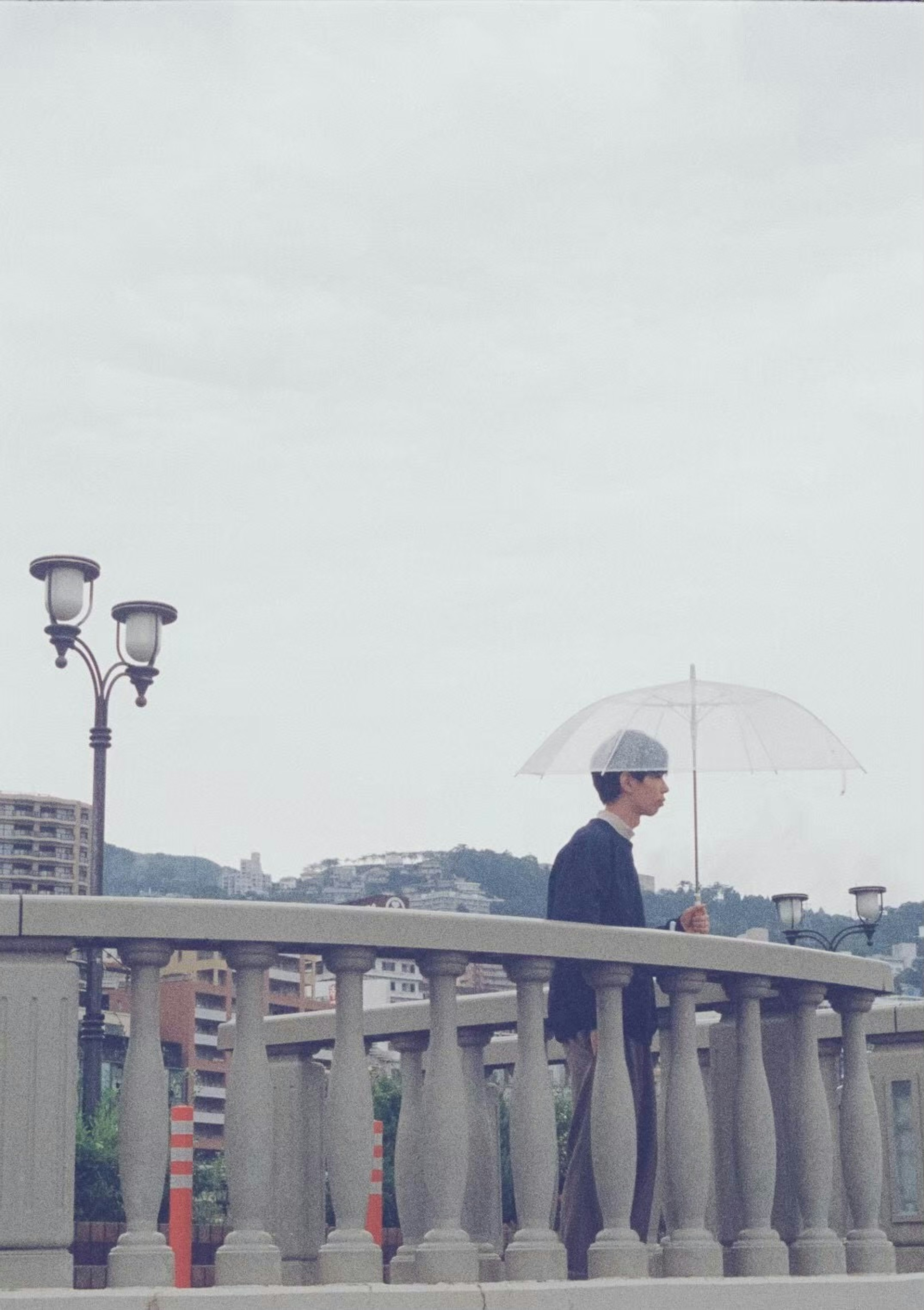 A man standing on a bridge holding an umbrella