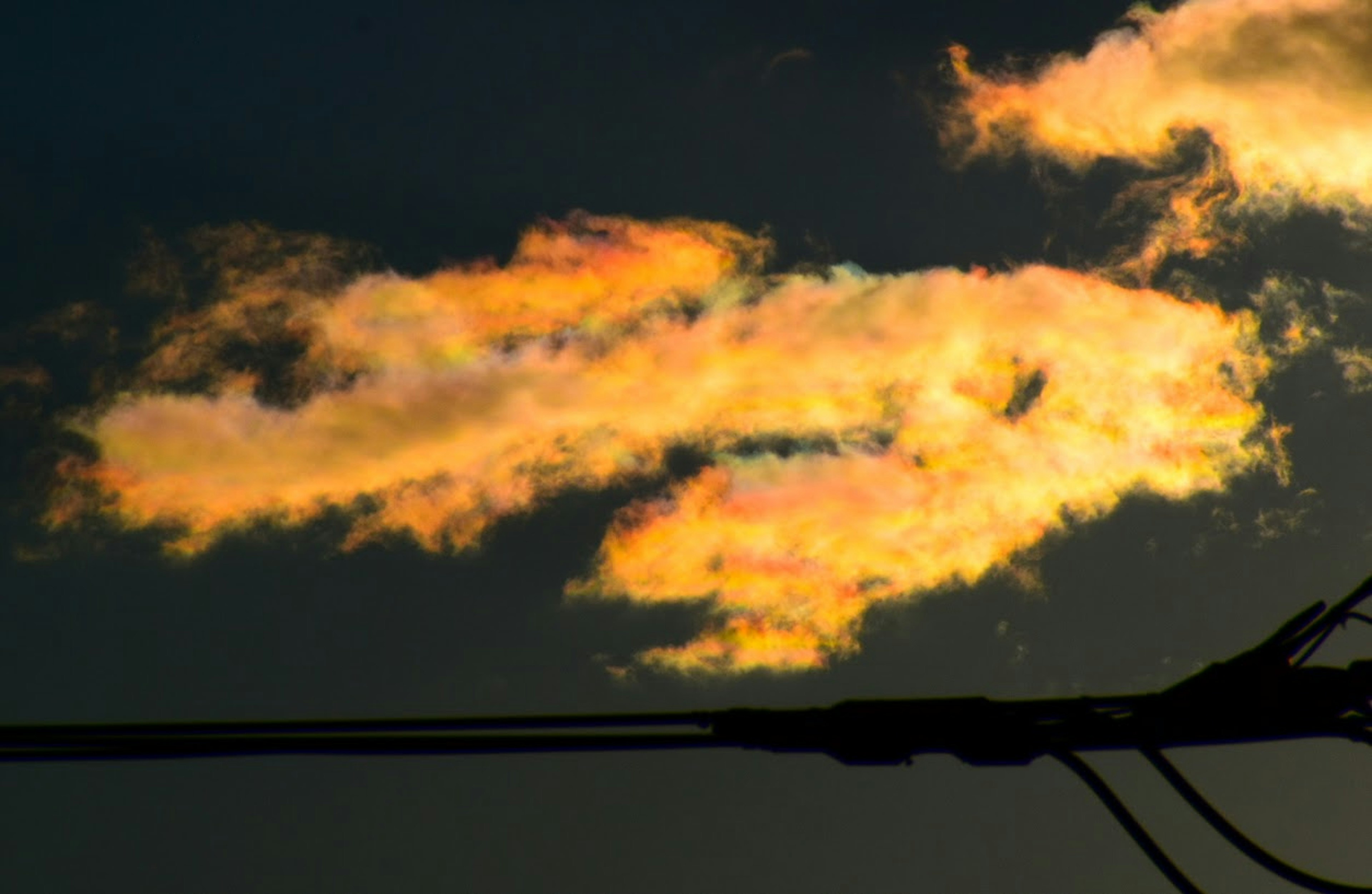 Nubes iluminadas por los colores del atardecer con siluetas de líneas eléctricas