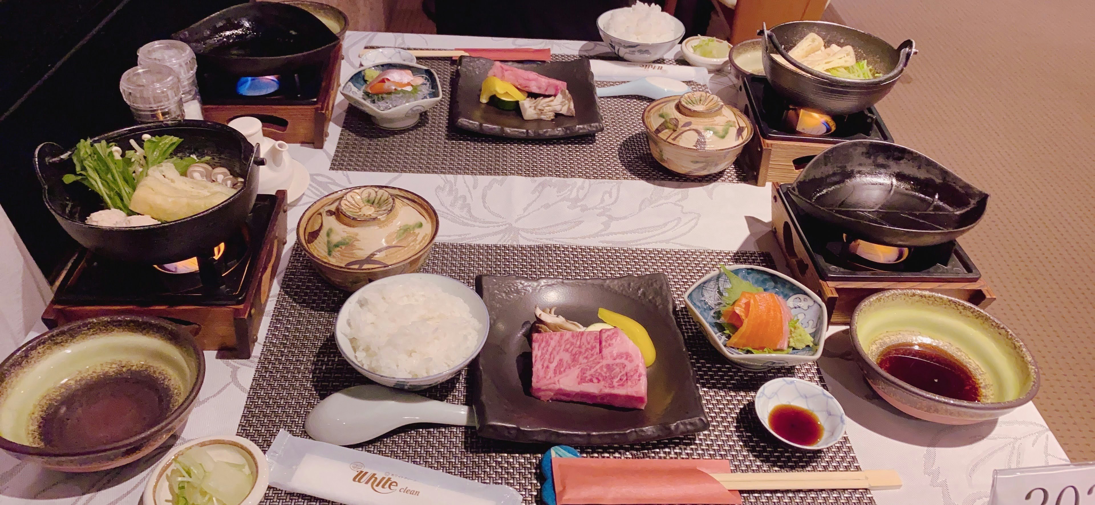 Una mesa con varios platos japoneses y ollas calientes