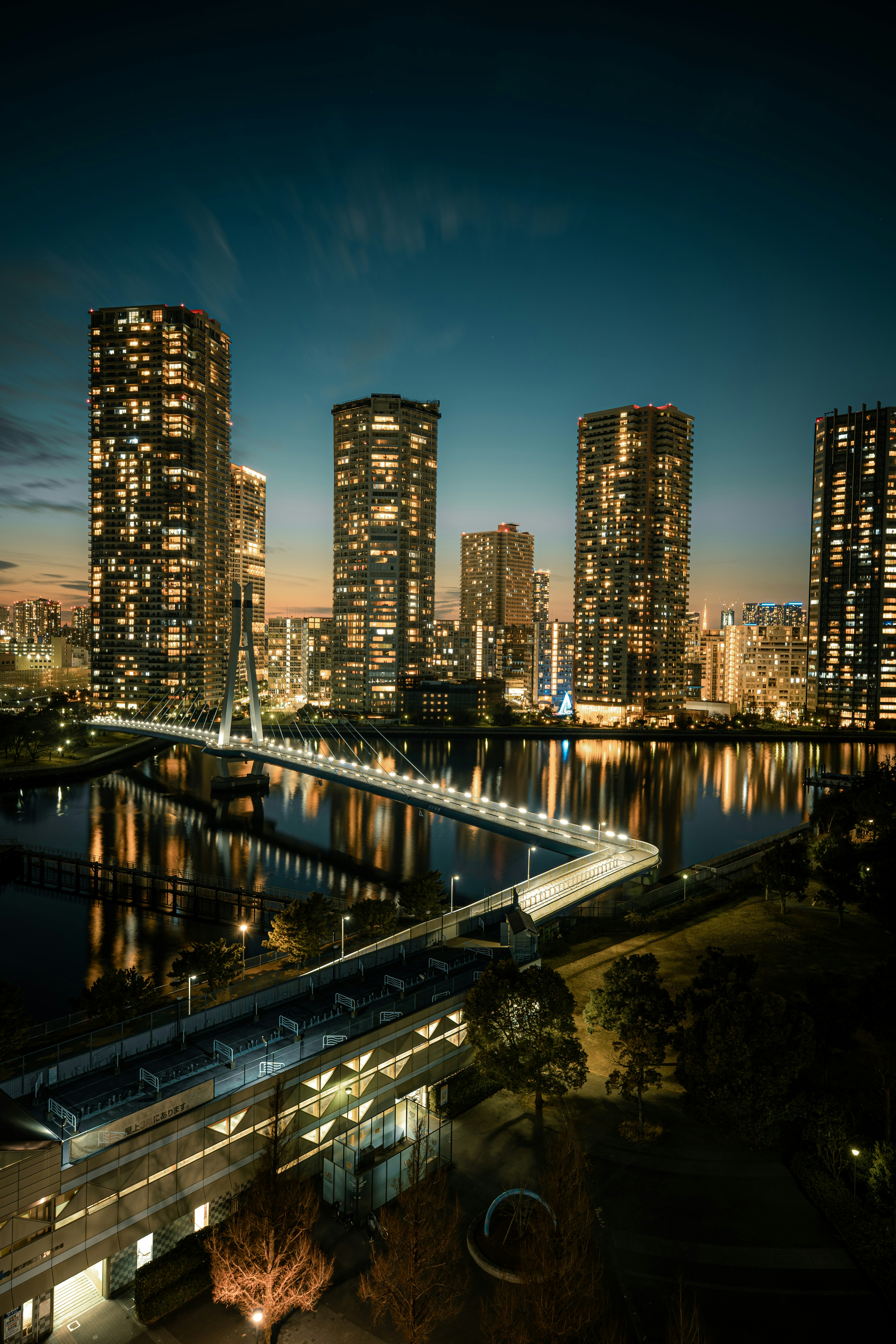 Beautiful cityscape at night with high-rise buildings and reflections on water