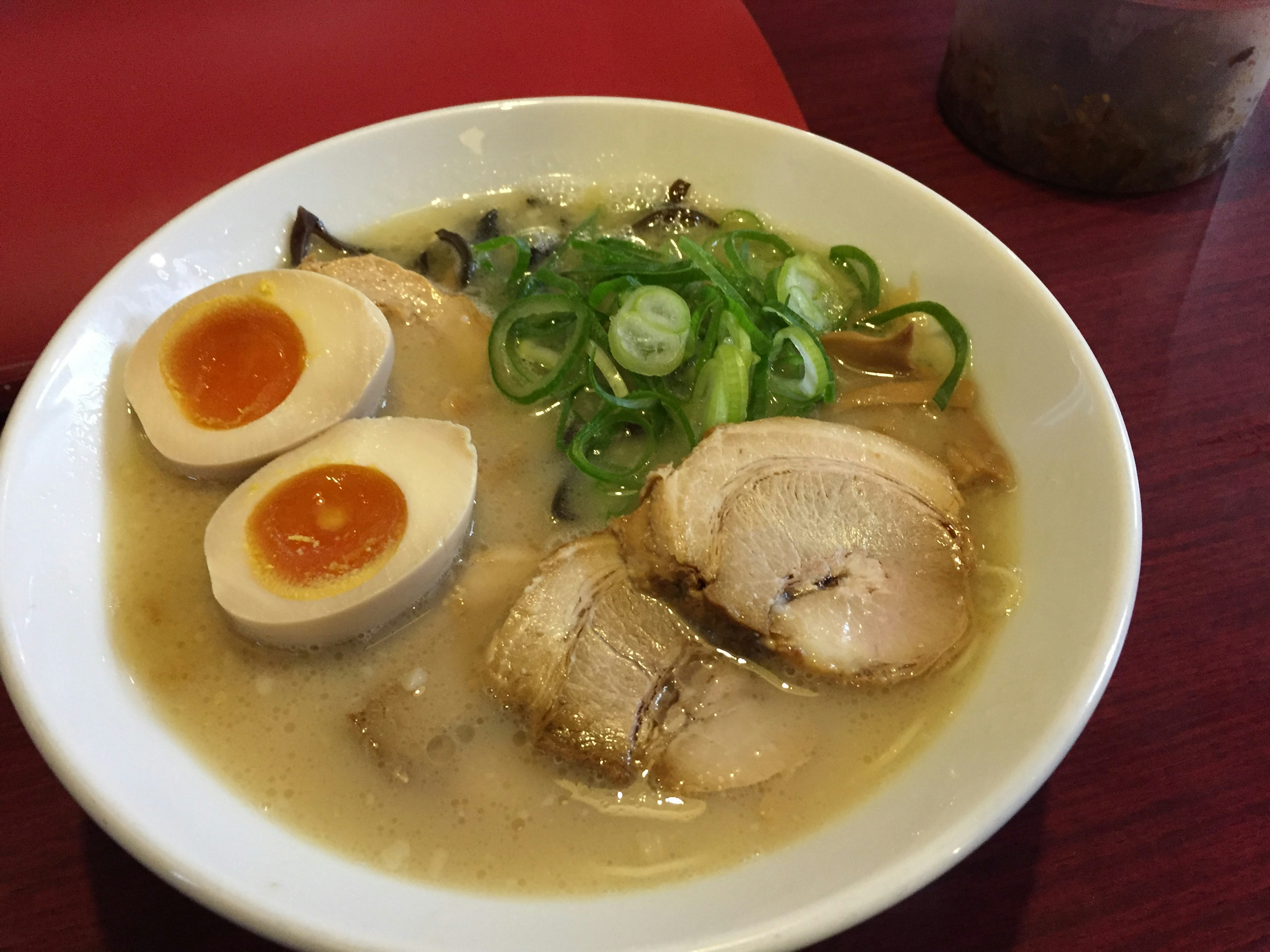 Tazón de ramen con caldo blanco cubierto con cerdo en rodajas y huevos pasados por agua